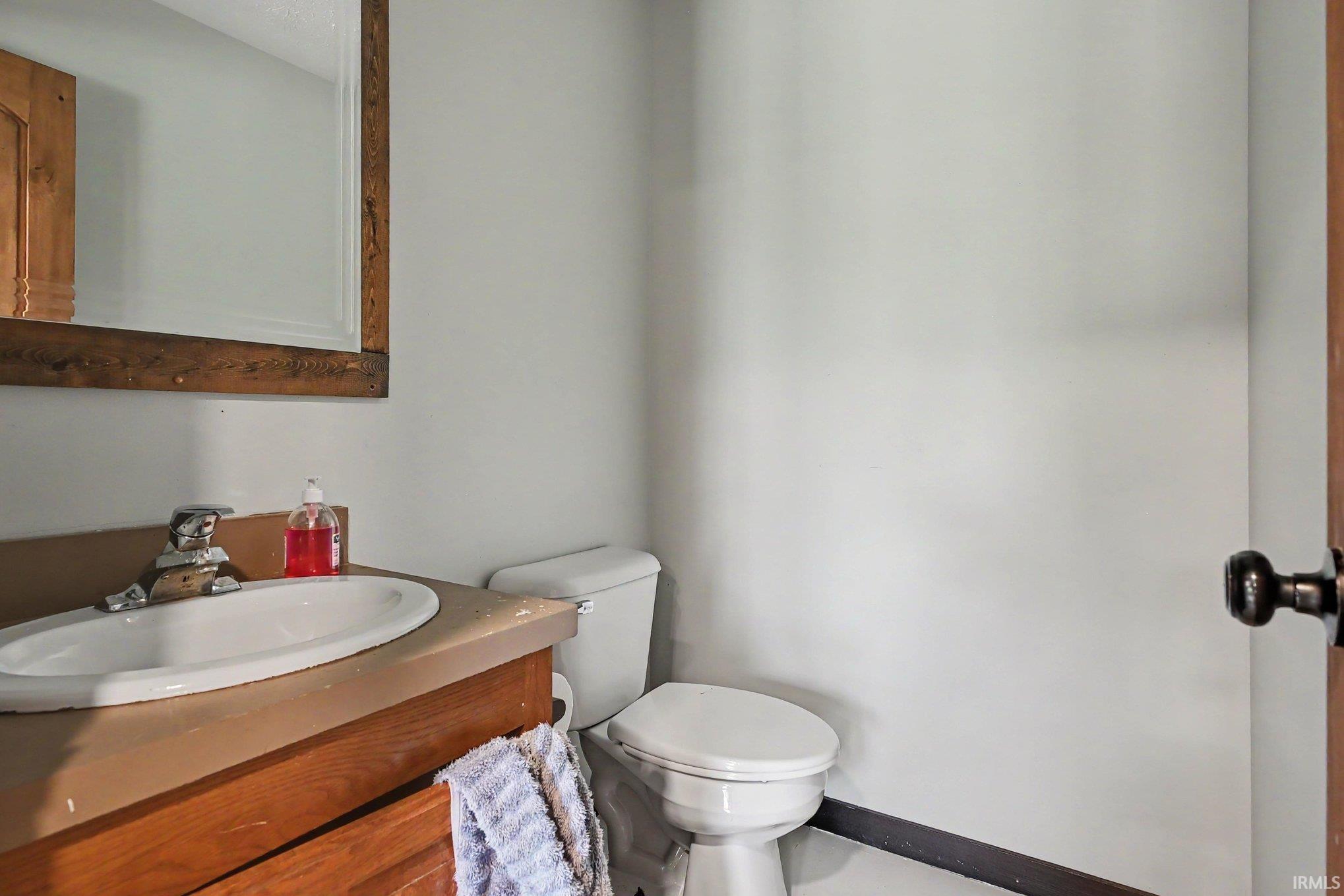 Bathroom featuring a wood-framed mirror, an integrated sink vanity with wood-finish cabinetry, and a two-piece toilet