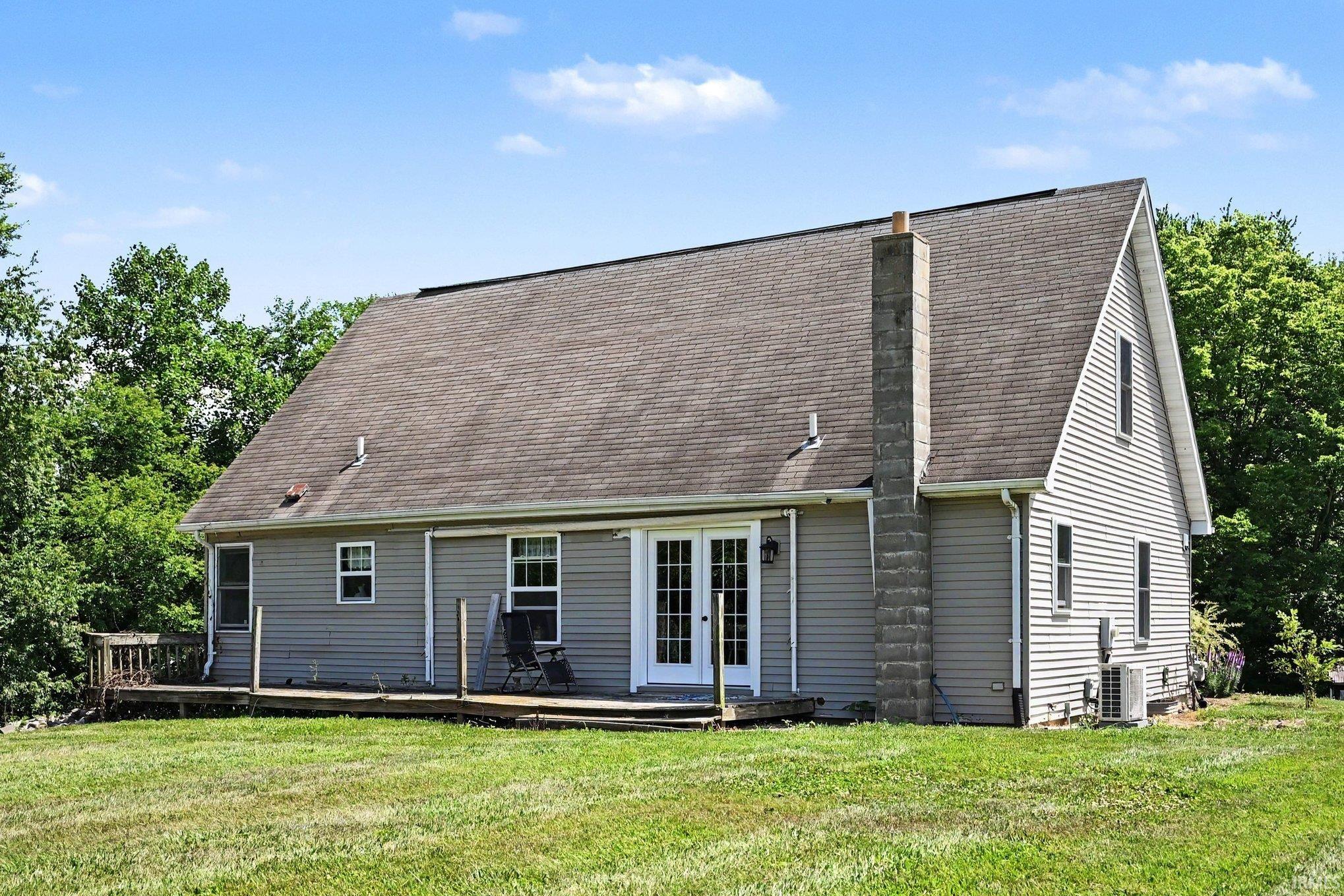 Rear exterior with a pitched shingle roof, gray horizontal siding, and a deck with wood railings
