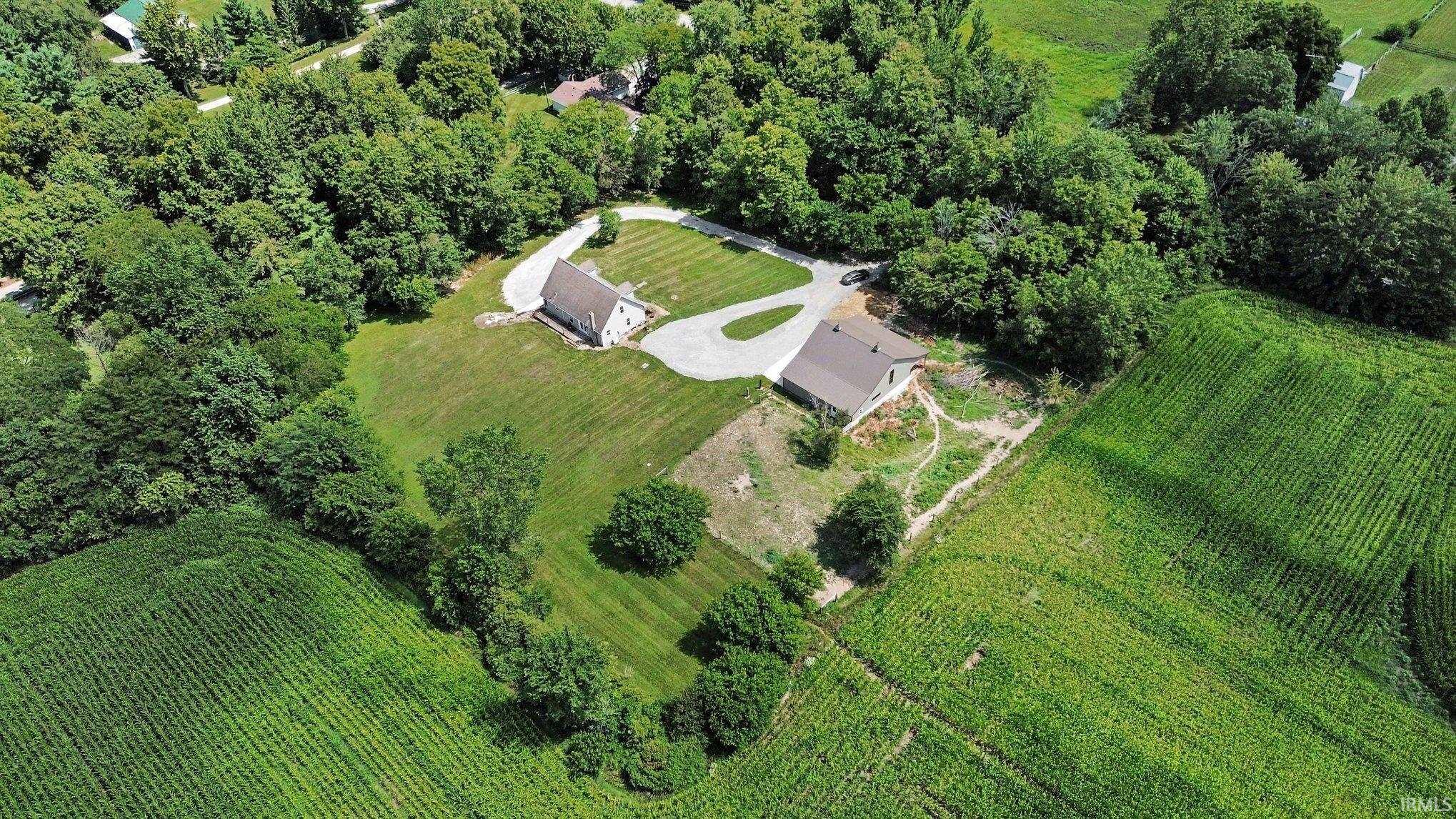Expansive property featuring two distinct structures nestled within a verdant, treed landscape