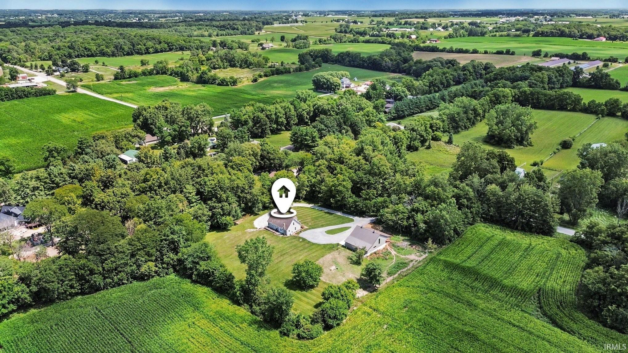 Aerial perspective showcasing a property surrounded by expansive green fields and mature trees
