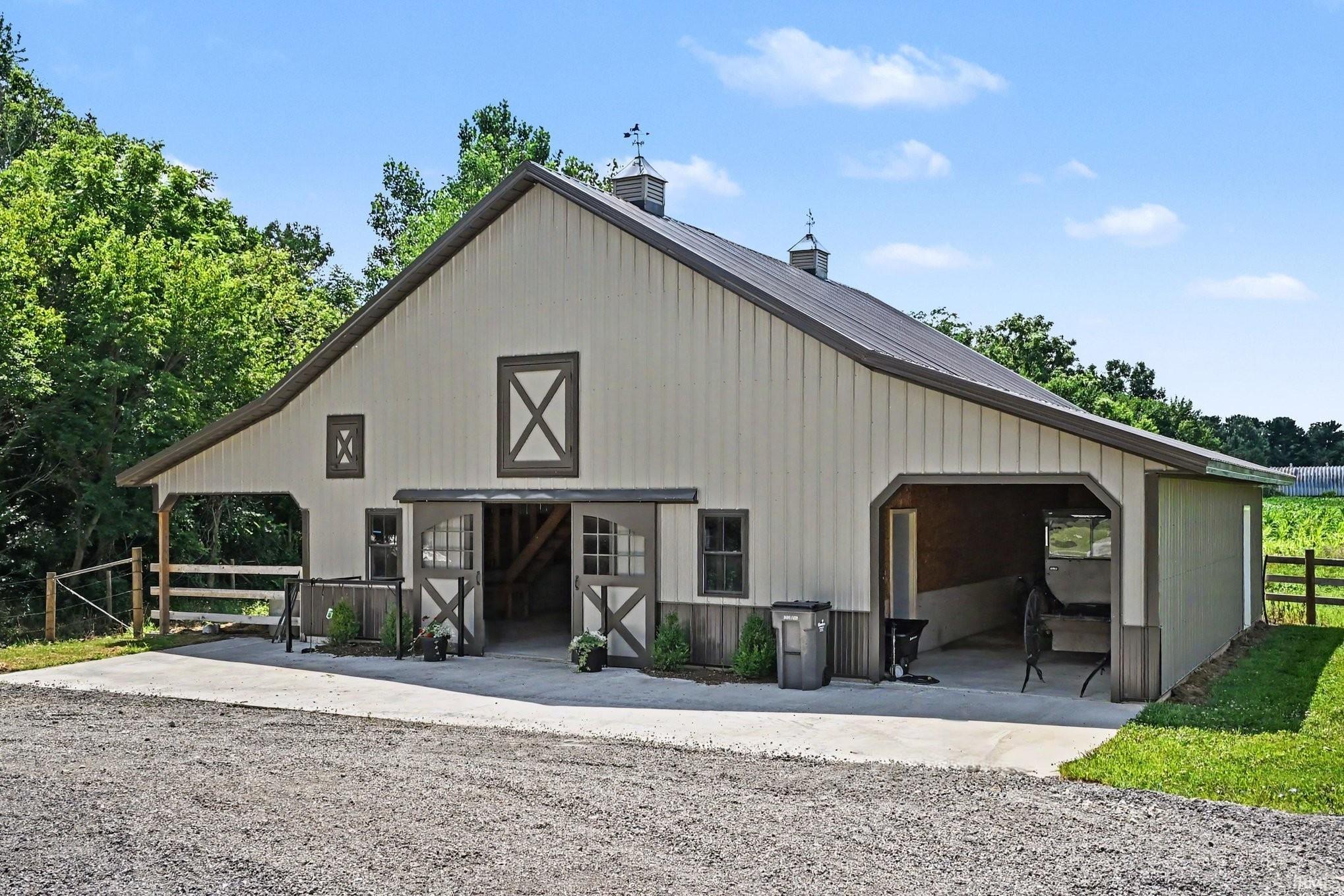 Expansive barn structure with a dark metal roof and light-colored siding