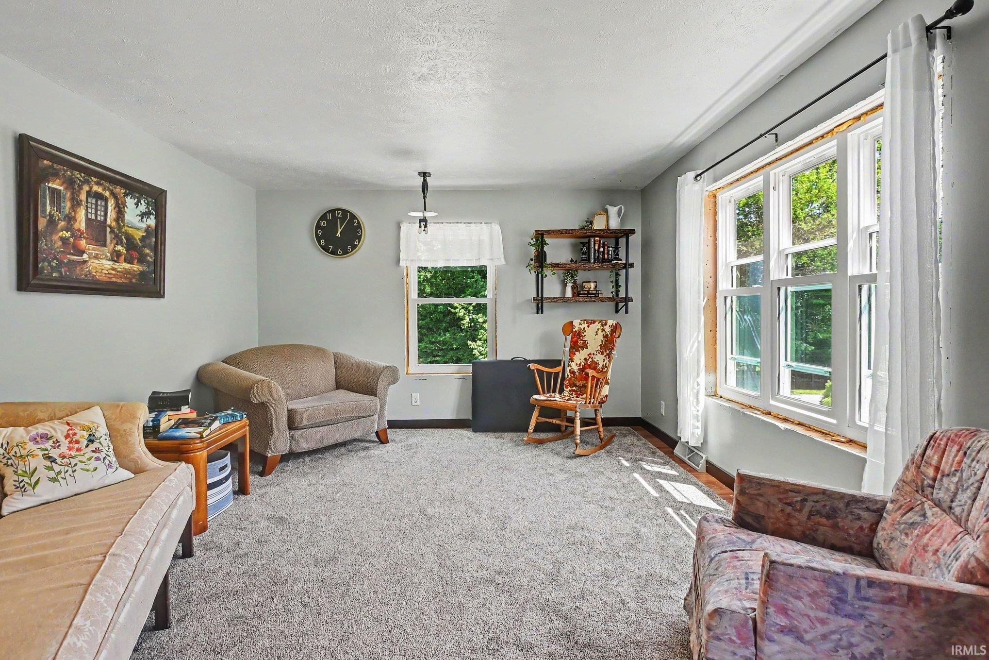 Spacious living area featuring light gray wall paint and gray carpet flooring