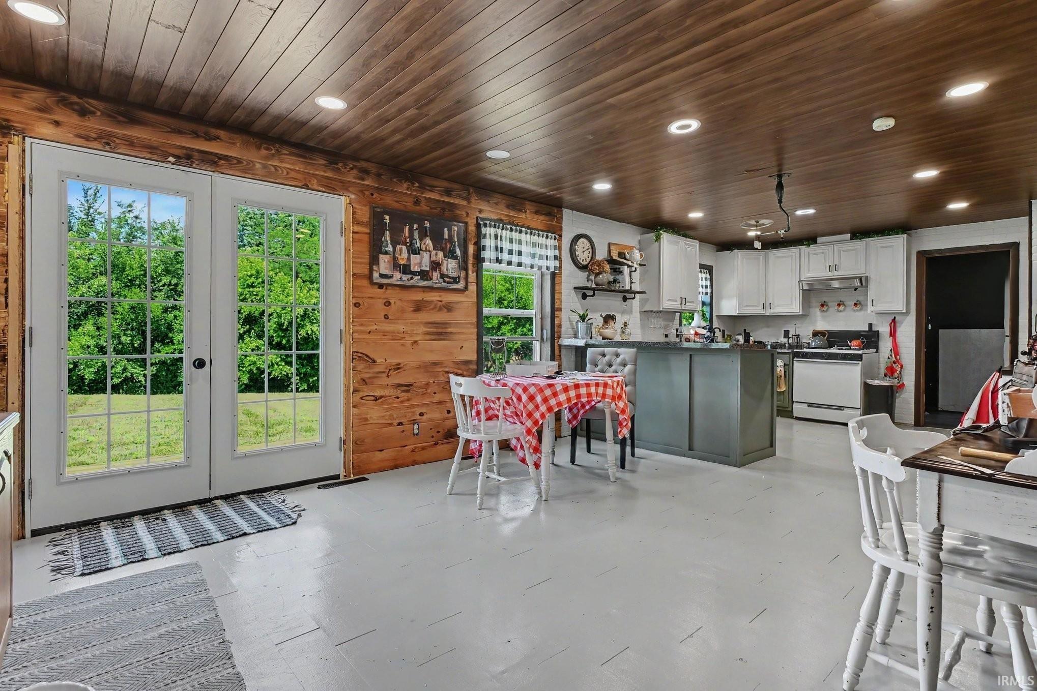 Kitchen featuring light-toned flooring, white upper cabinetry, and a central island with a contrasting finish