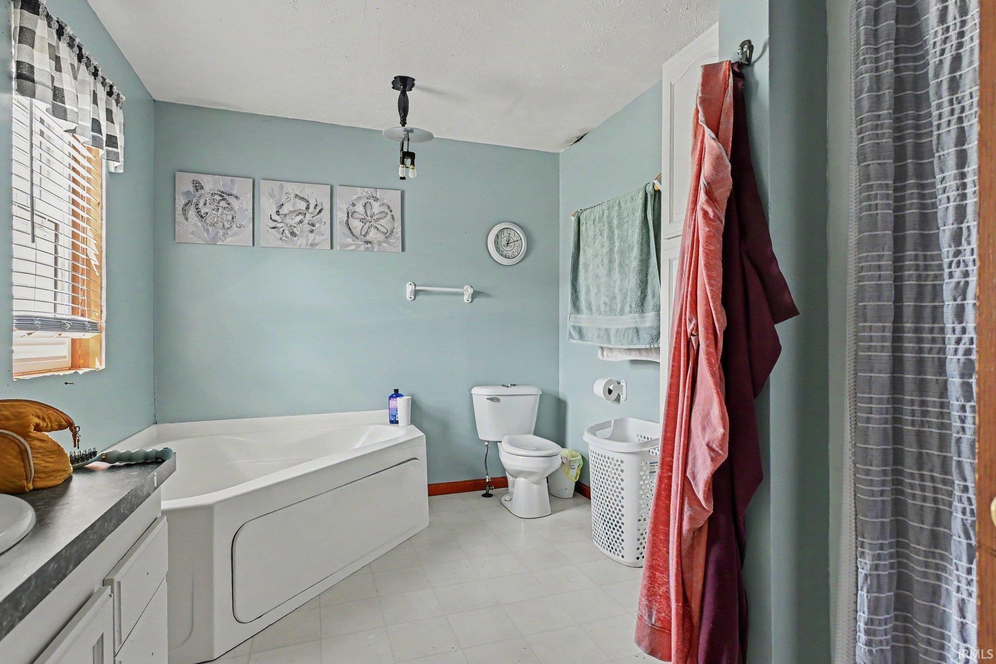Bathroom featuring a corner soaking tub and light blue walls