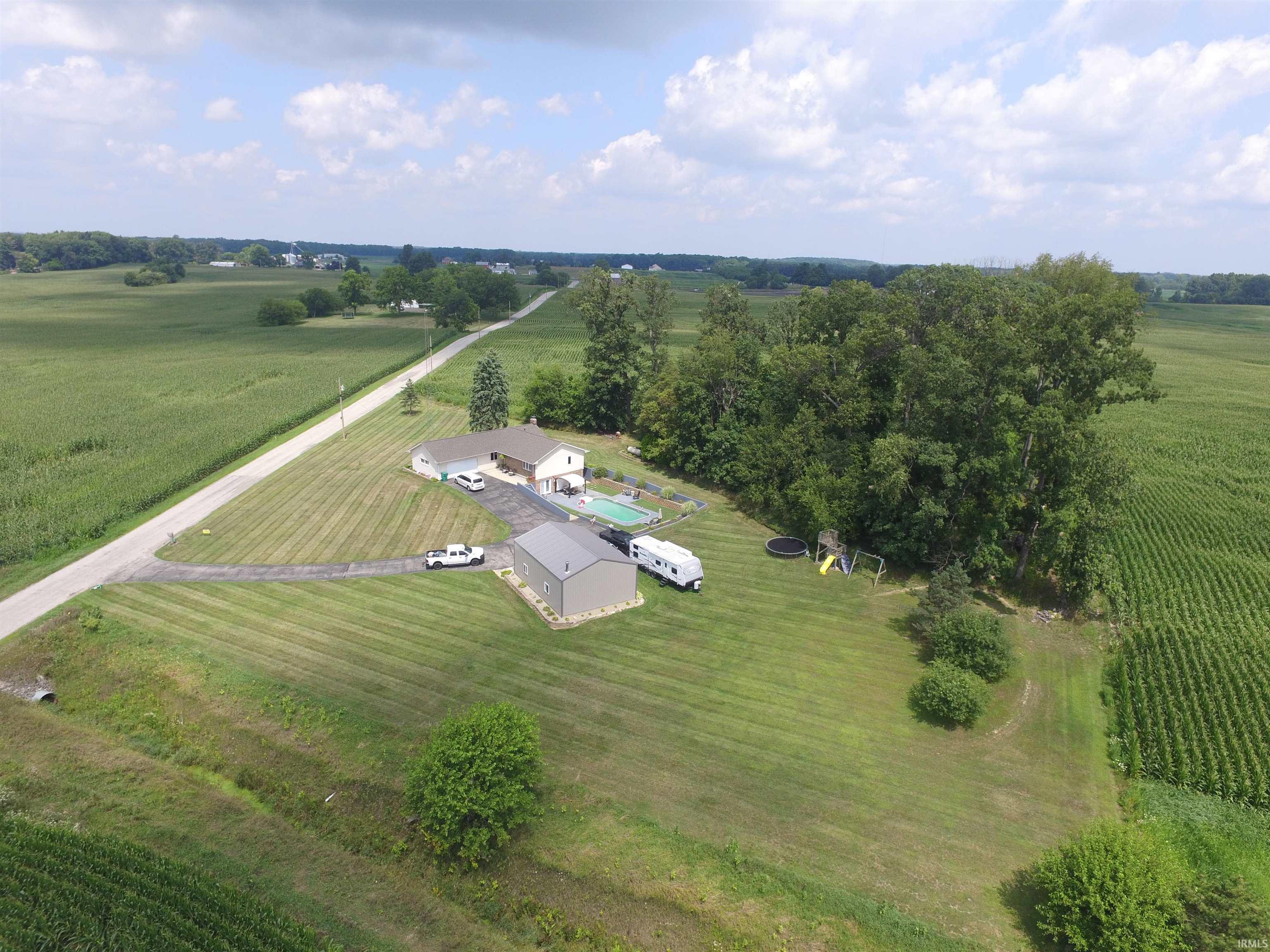 Expansive property featuring a single-story residence, detached outbuilding, paved driveway, and an outdoor swimming pool