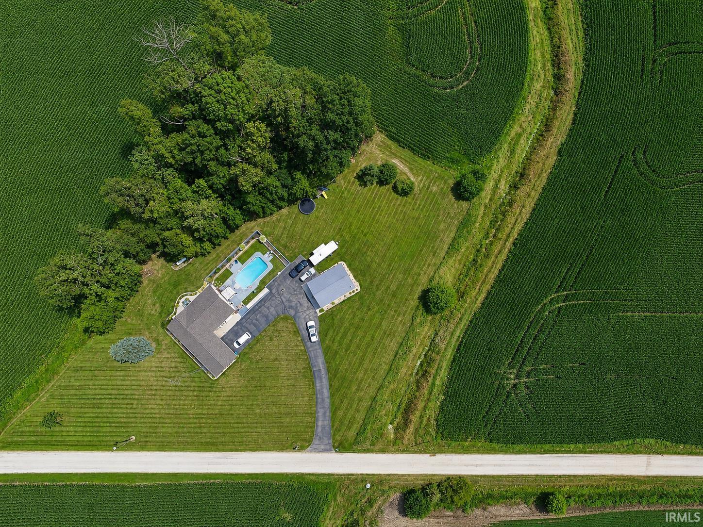 Expansive property featuring a private swimming pool, mature trees, substantial paved driveway, and additional outbuilding