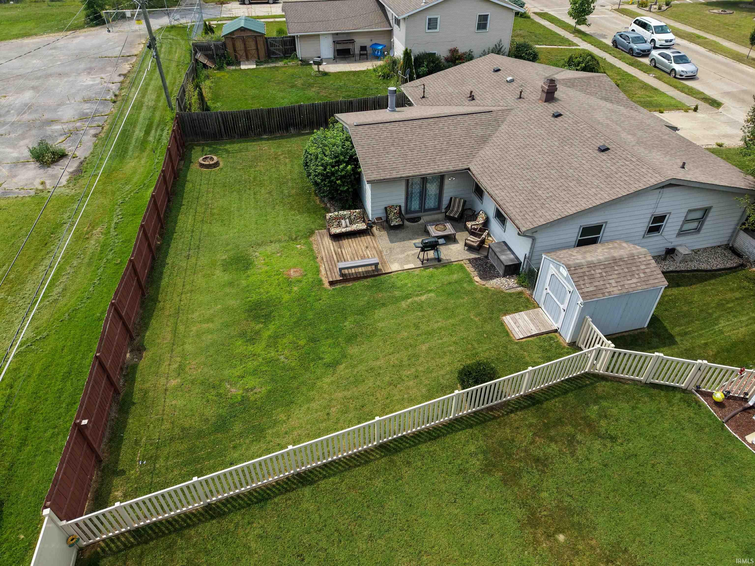 Expansive backyard featuring a concrete patio, wood deck, and a detached storage shed