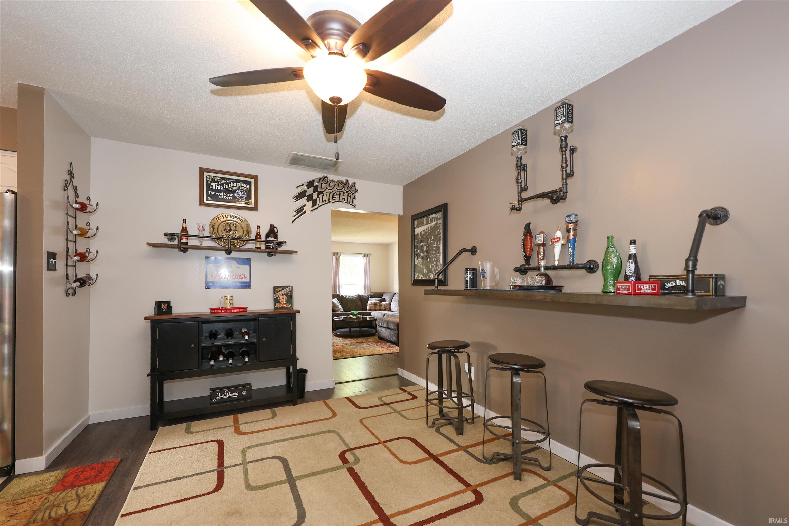 Built-in bar with dark wood-finish countertop, industrial-style wall sconces, and overhead ceiling fan