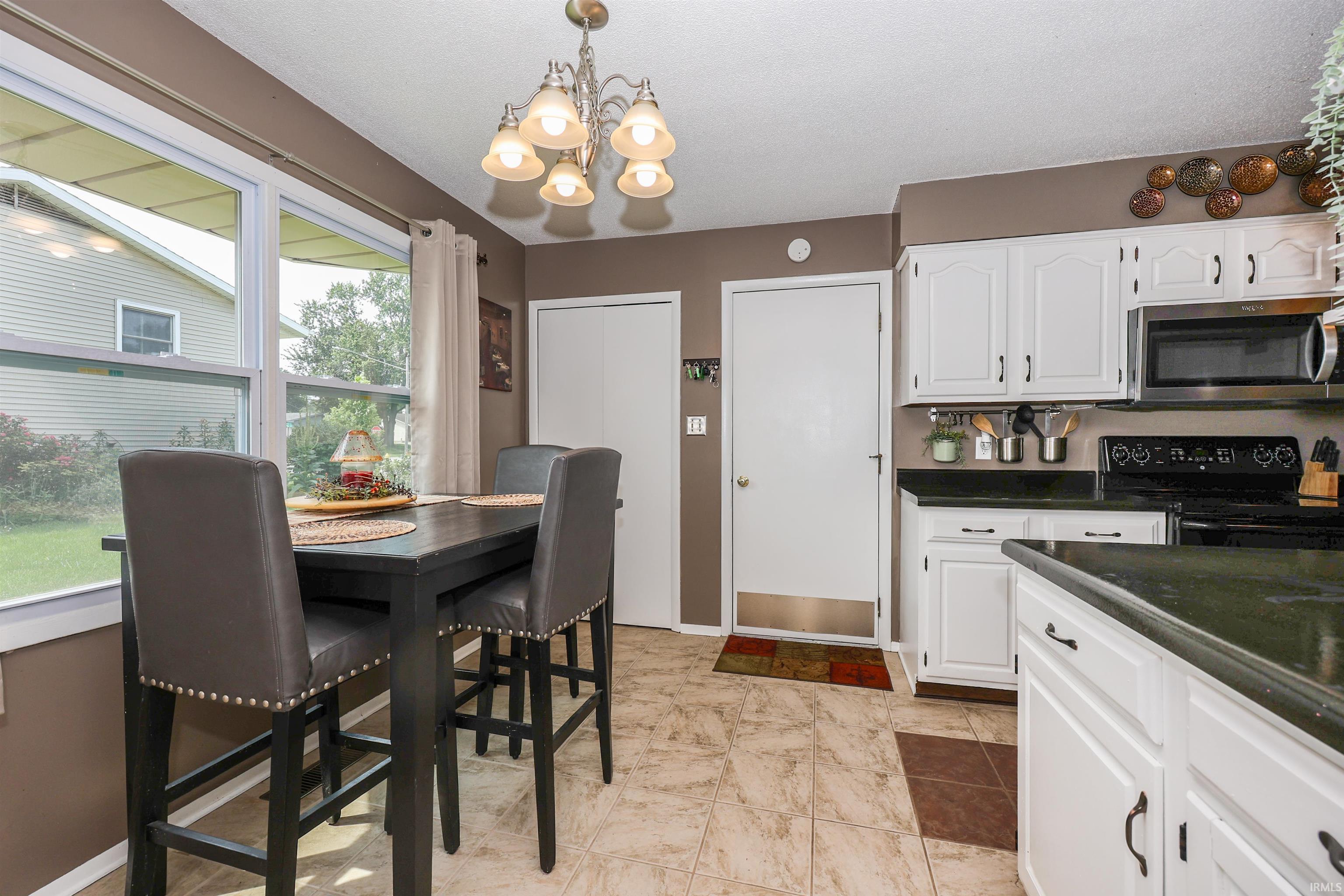 Kitchen dining area featuring white cabinetry, dark countertops, and tile flooring