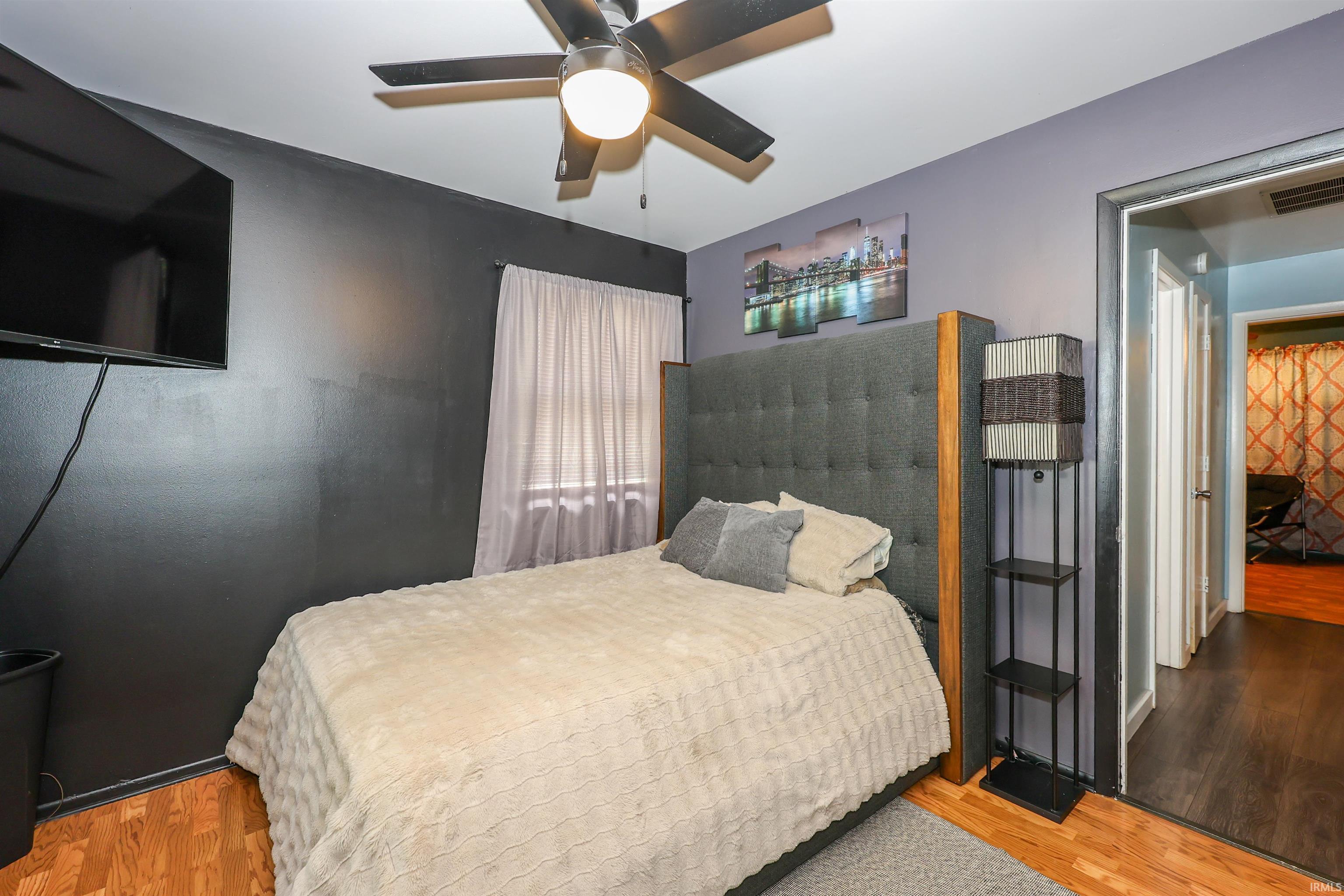 Bedroom featuring wood-finish flooring, a ceiling fan, and contrasting wall colors