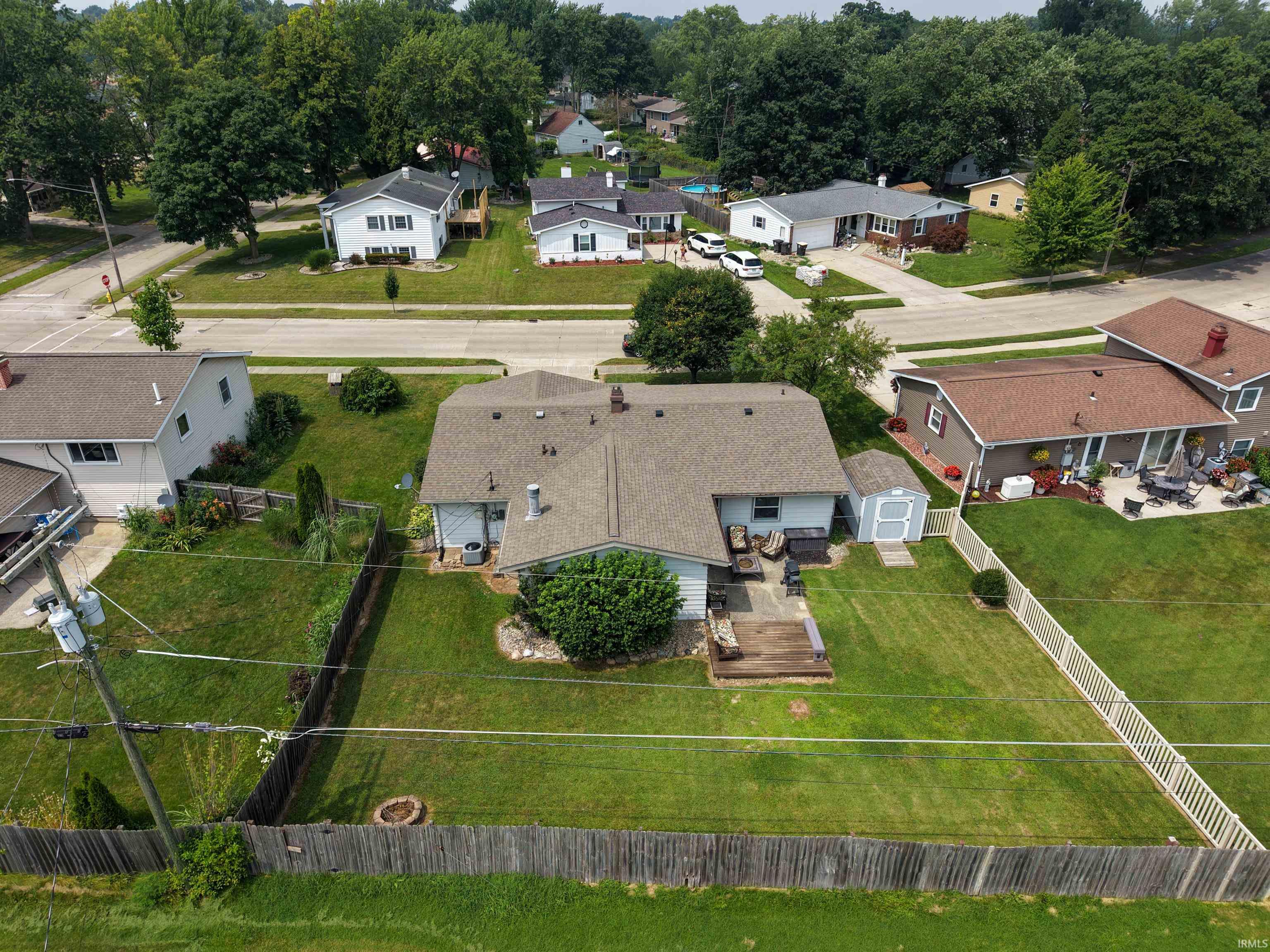 Expansive backyard featuring a large wooden deck, a detached storage shed, and a privacy fence