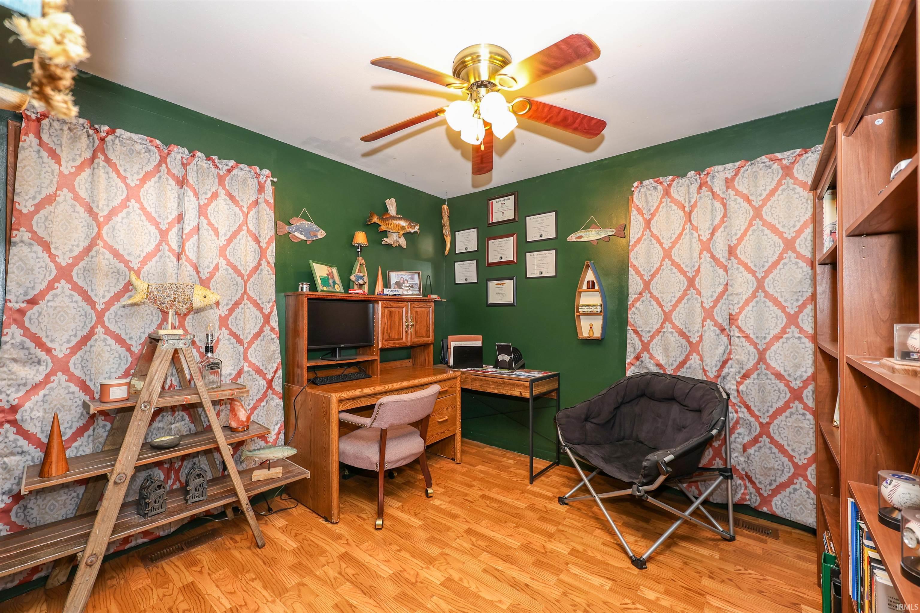 Room featuring wood-finish flooring, a ceiling fan with integrated lighting, and a full-height built-in bookshelf