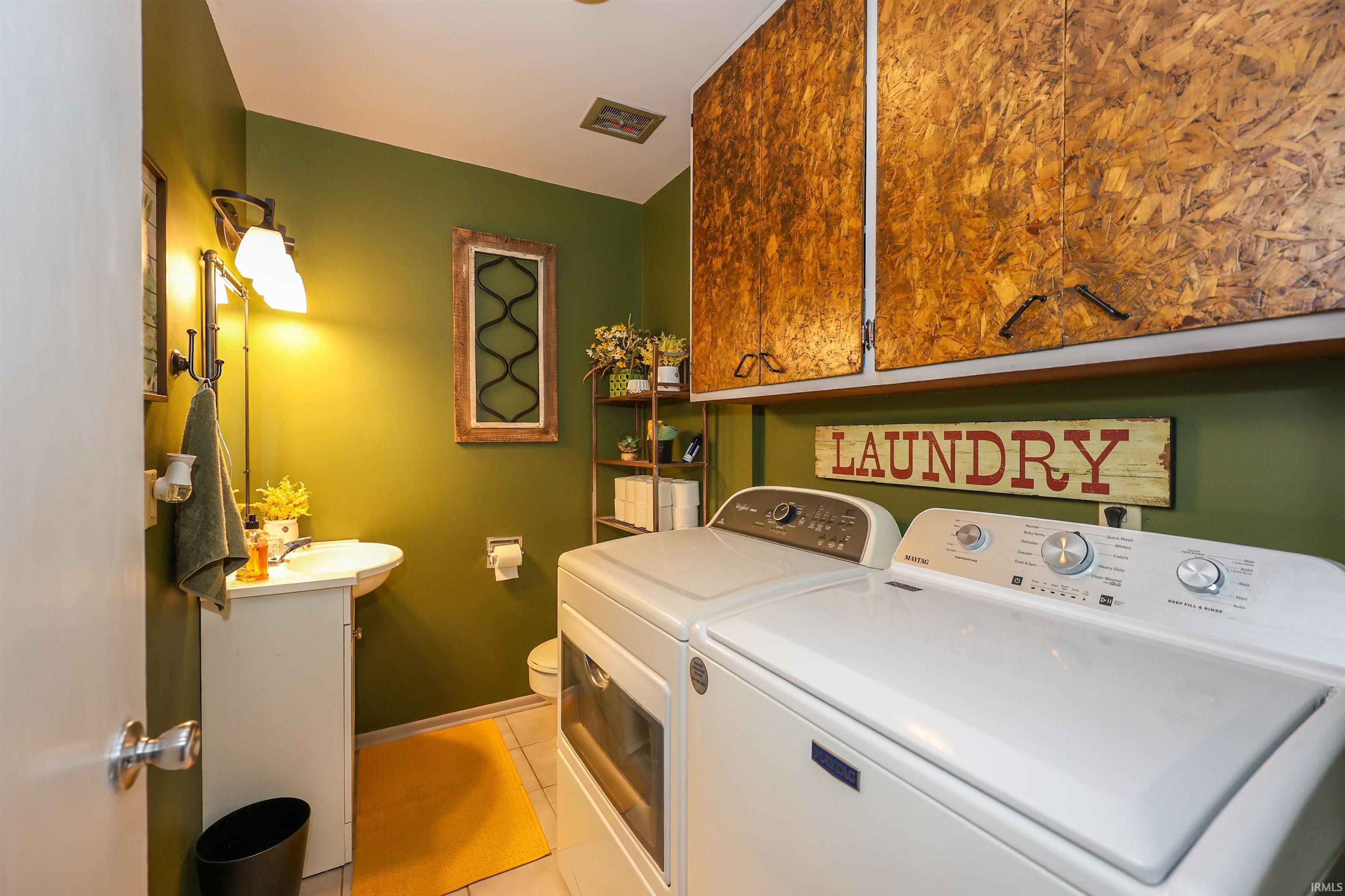Dedicated laundry area featuring overhead storage cabinets, a vanity sink, and a toilet