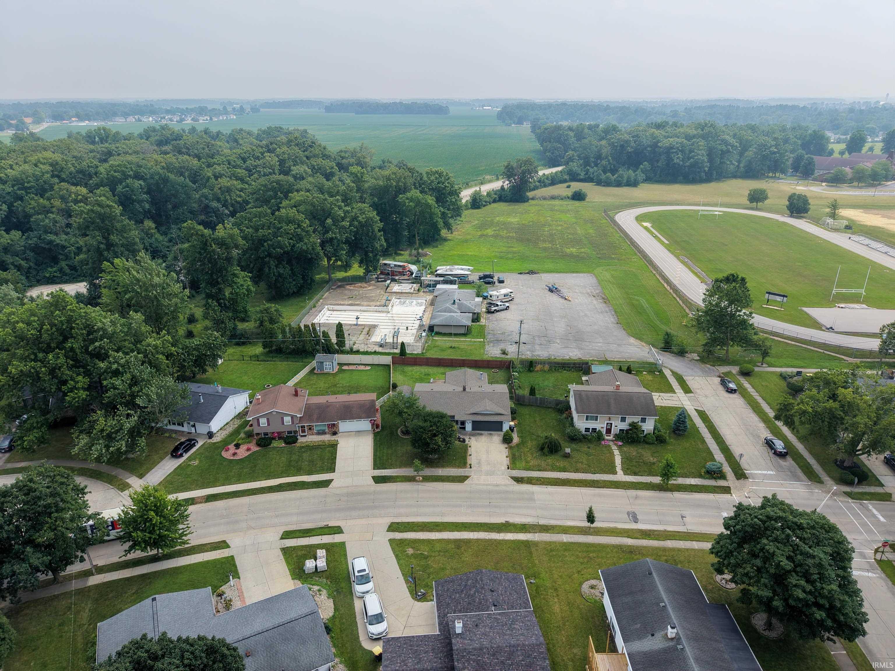 Aerial perspective showcasing a residential neighborhood with established homes, tree-lined streets, and surrounding green spaces