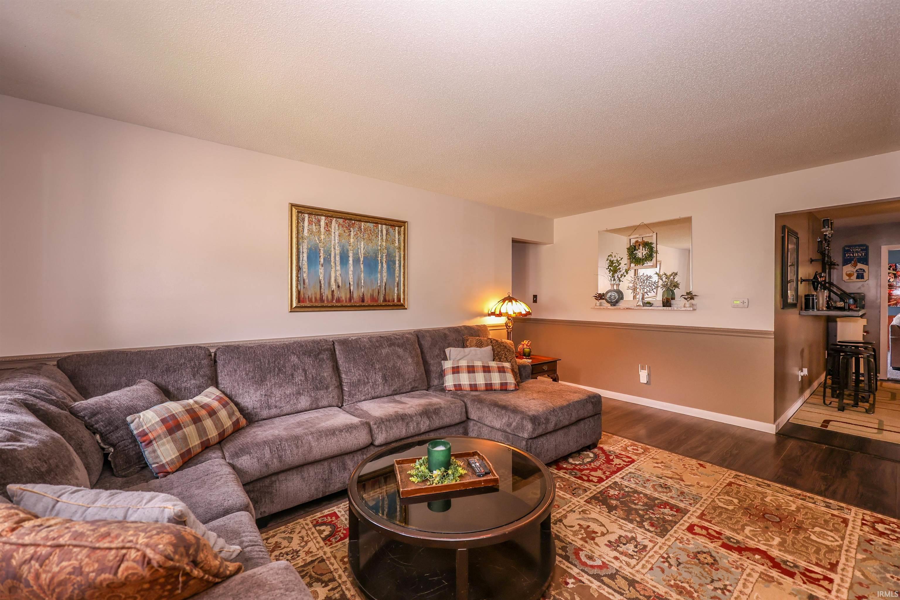 Living area featuring wood-finish flooring, a neutral color palette, and a half wall with a pass-through opening