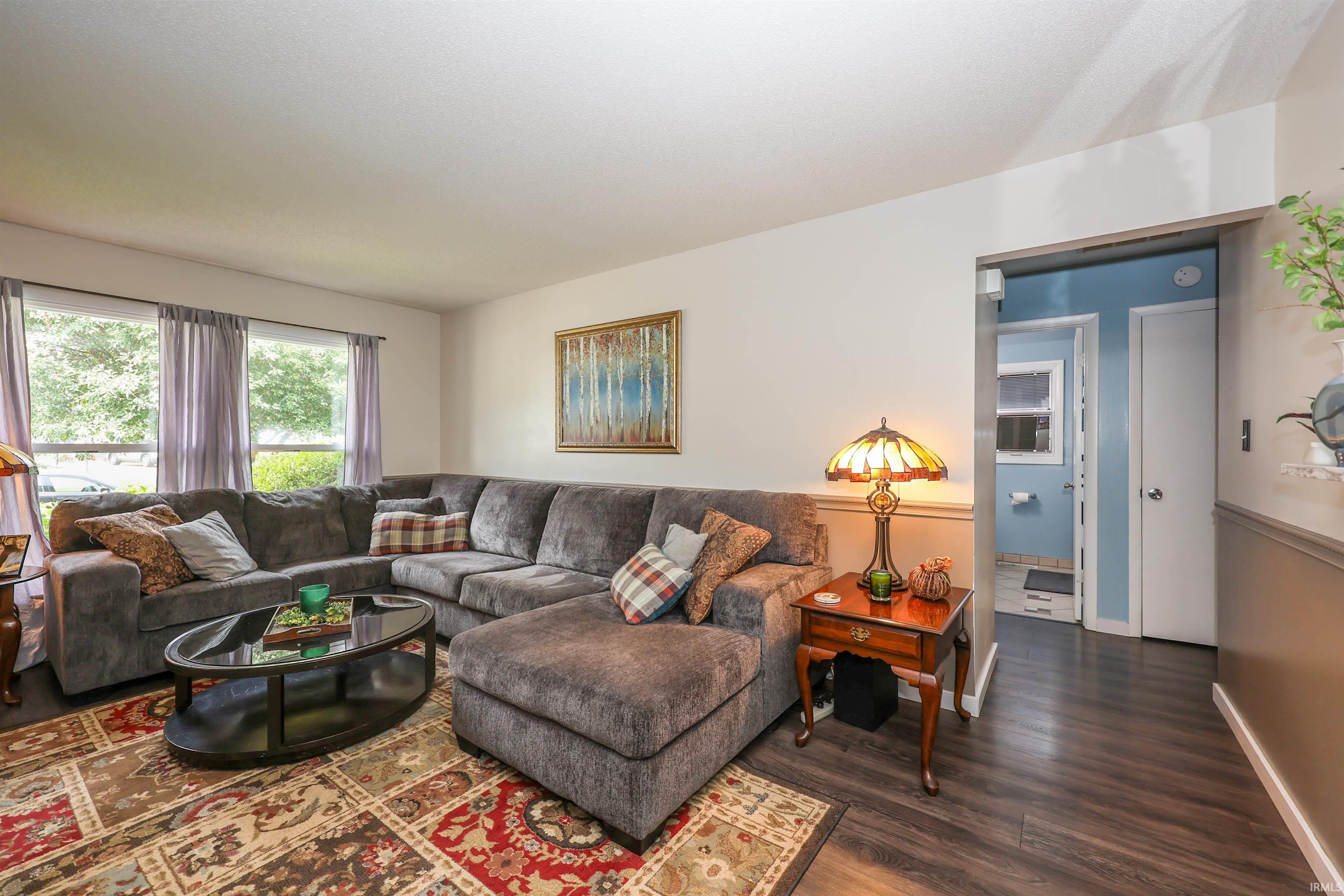 Spacious living area featuring large windows, wood-finish flooring, and crown molding