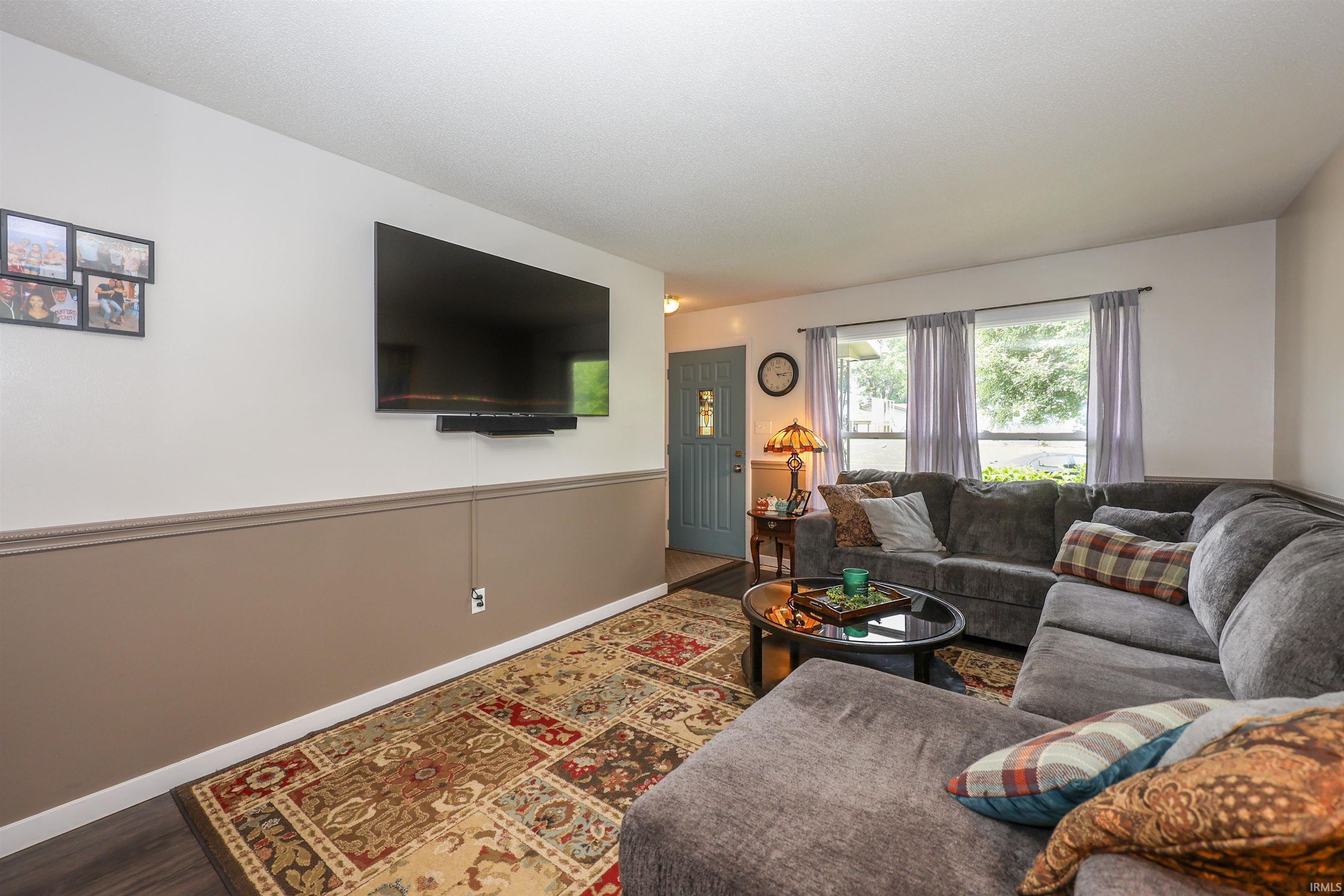 Living room featuring wood-finish flooring, two-tone painted walls with chair rail molding, and multiple windows
