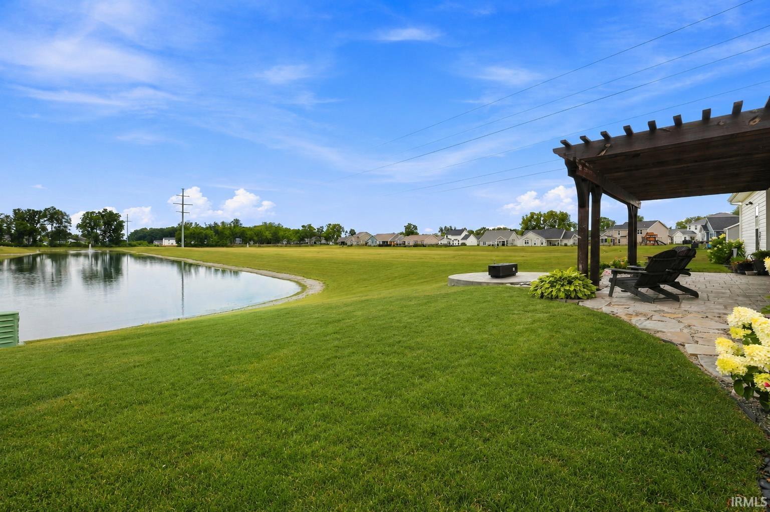Expansive backyard featuring a stone patio, a wooden pergola, and a circular concrete pad