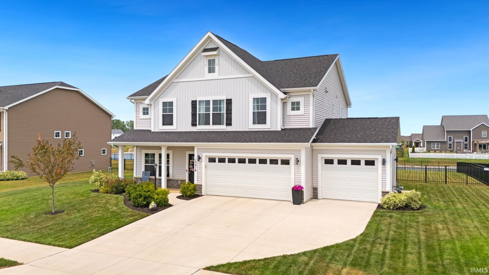 Two-story residence featuring light gray siding, dark shingle roofing, and a prominent front gable