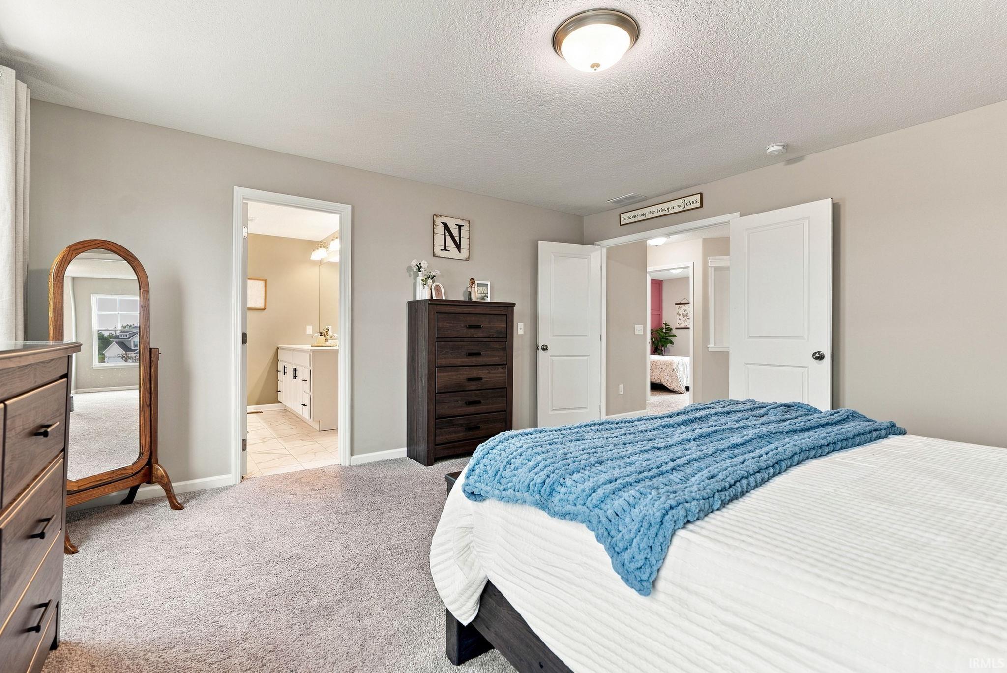Carpeted bedroom with neutral wall tones and a ceiling-mounted light fixture