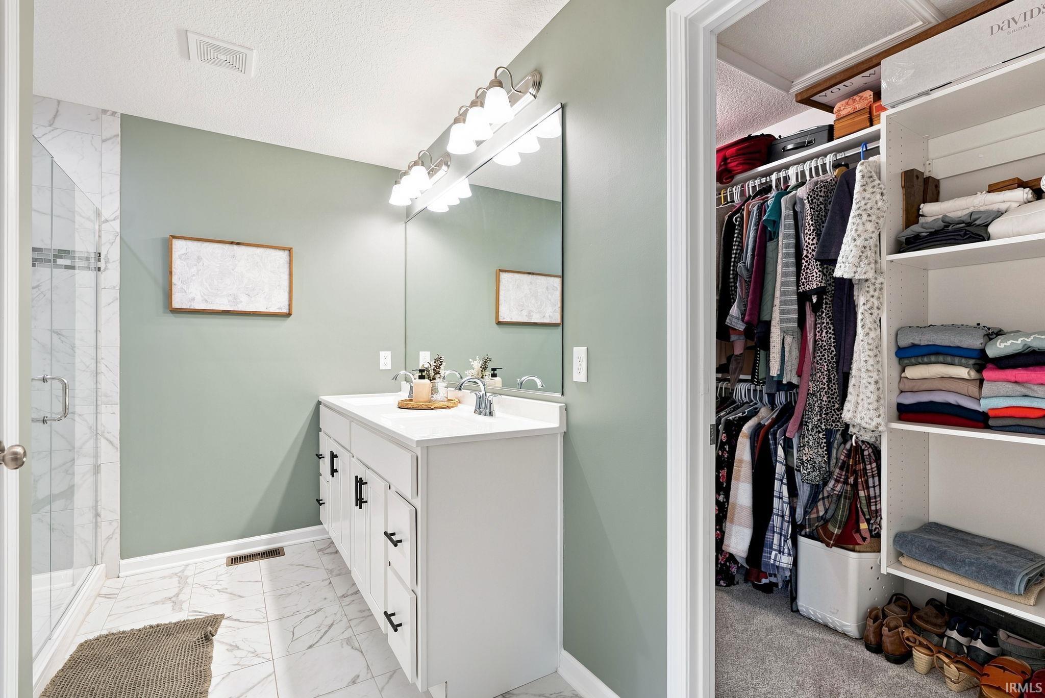 Bathroom featuring a white dual-sink vanity with dark hardware, a large mirror, and an overhead light fixture