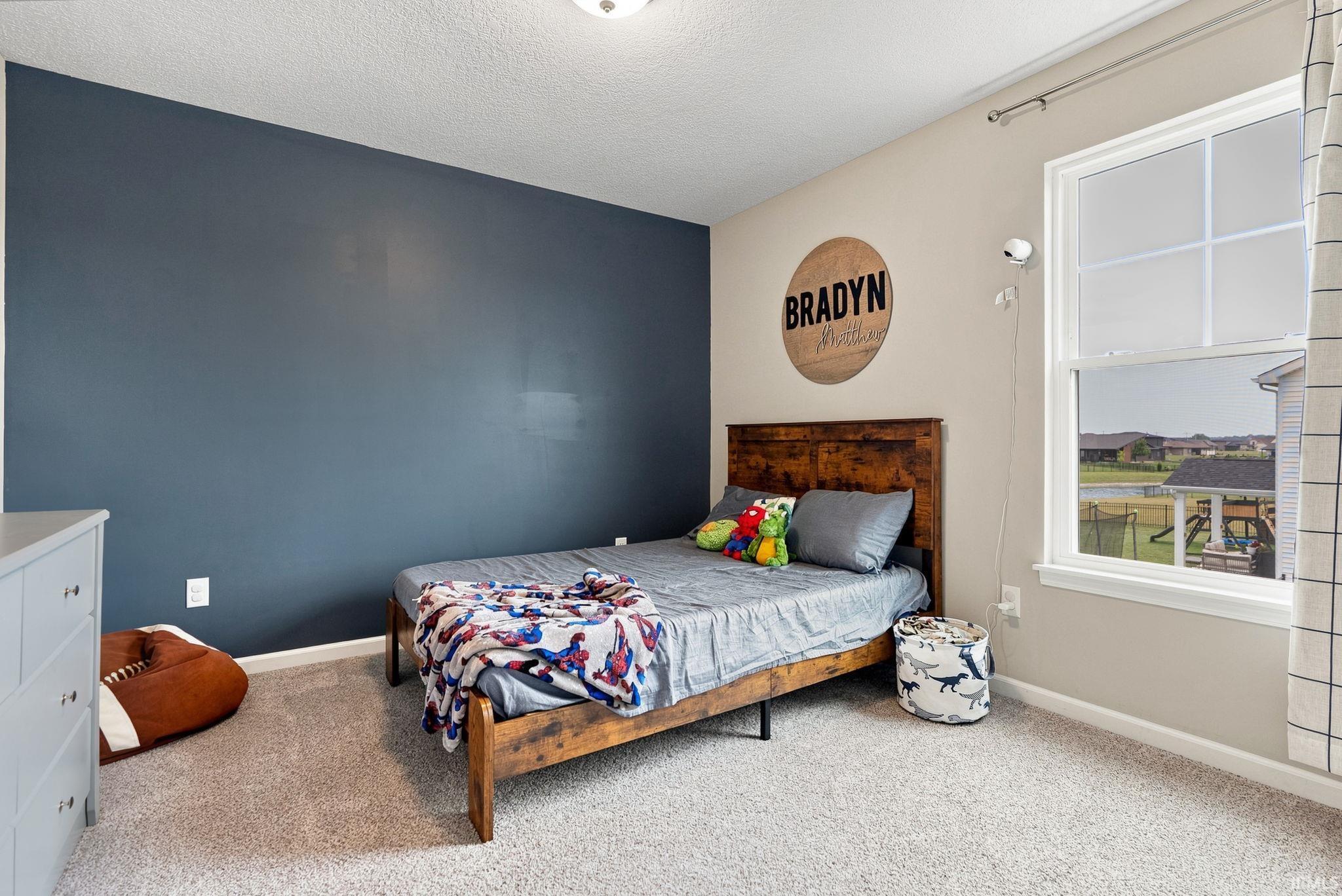 Neutral-toned wall with a contrasting accent wall, double-pane window, and carpet flooring