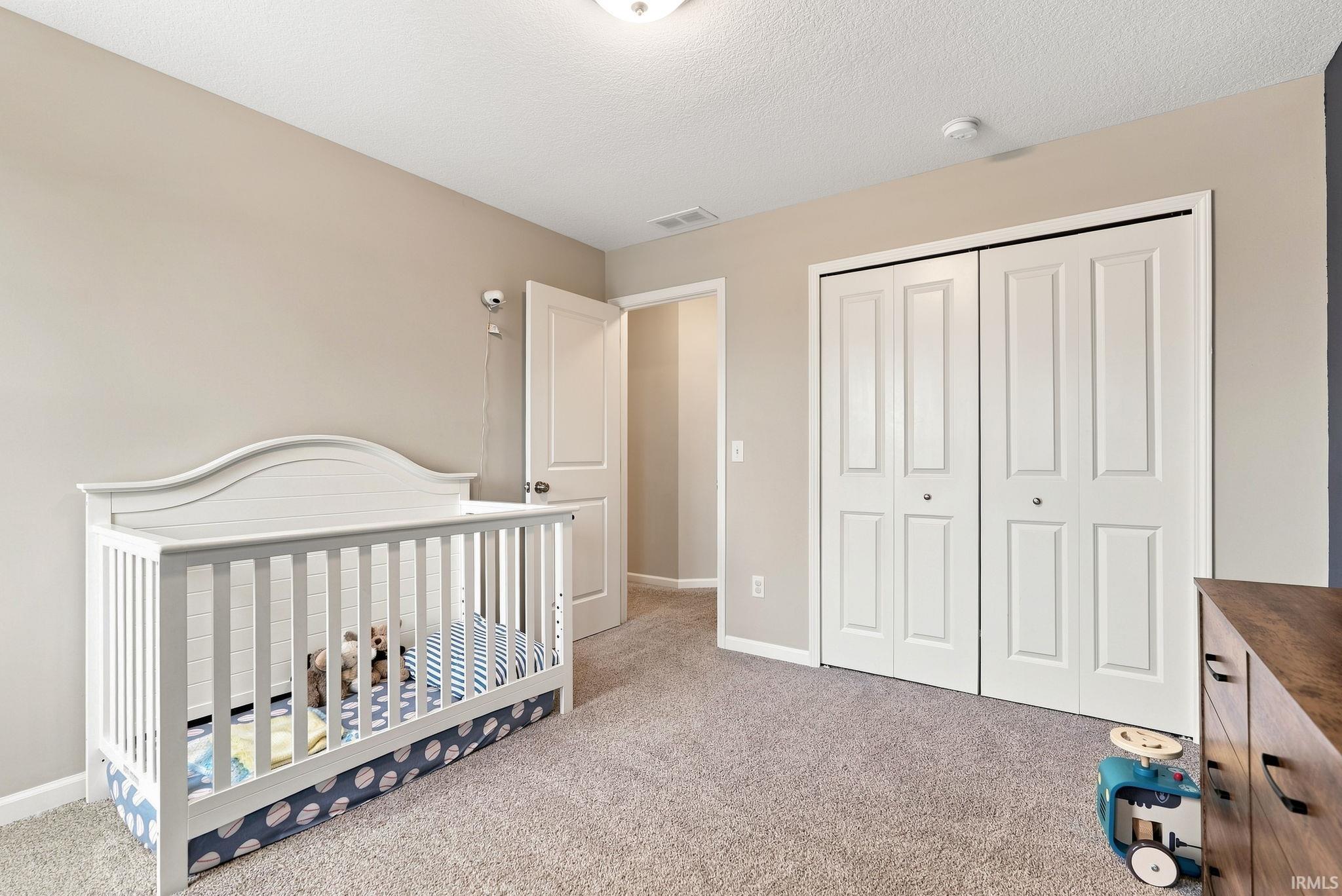 Carpeted bedroom with neutral wall tones and a ceiling-mounted light fixture