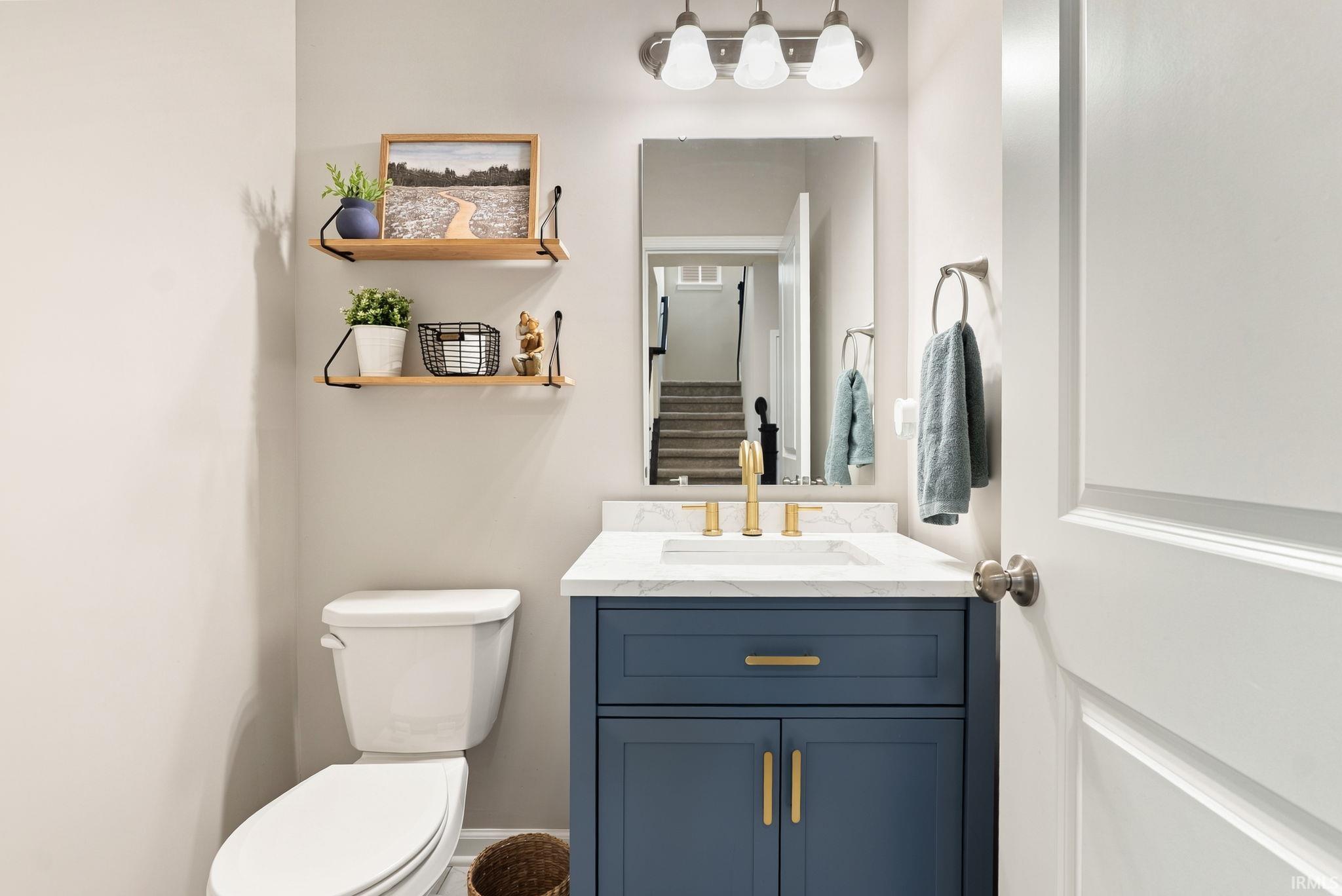 Powder room featuring a blue vanity with gold hardware, a white countertop, and a rectangular mirror