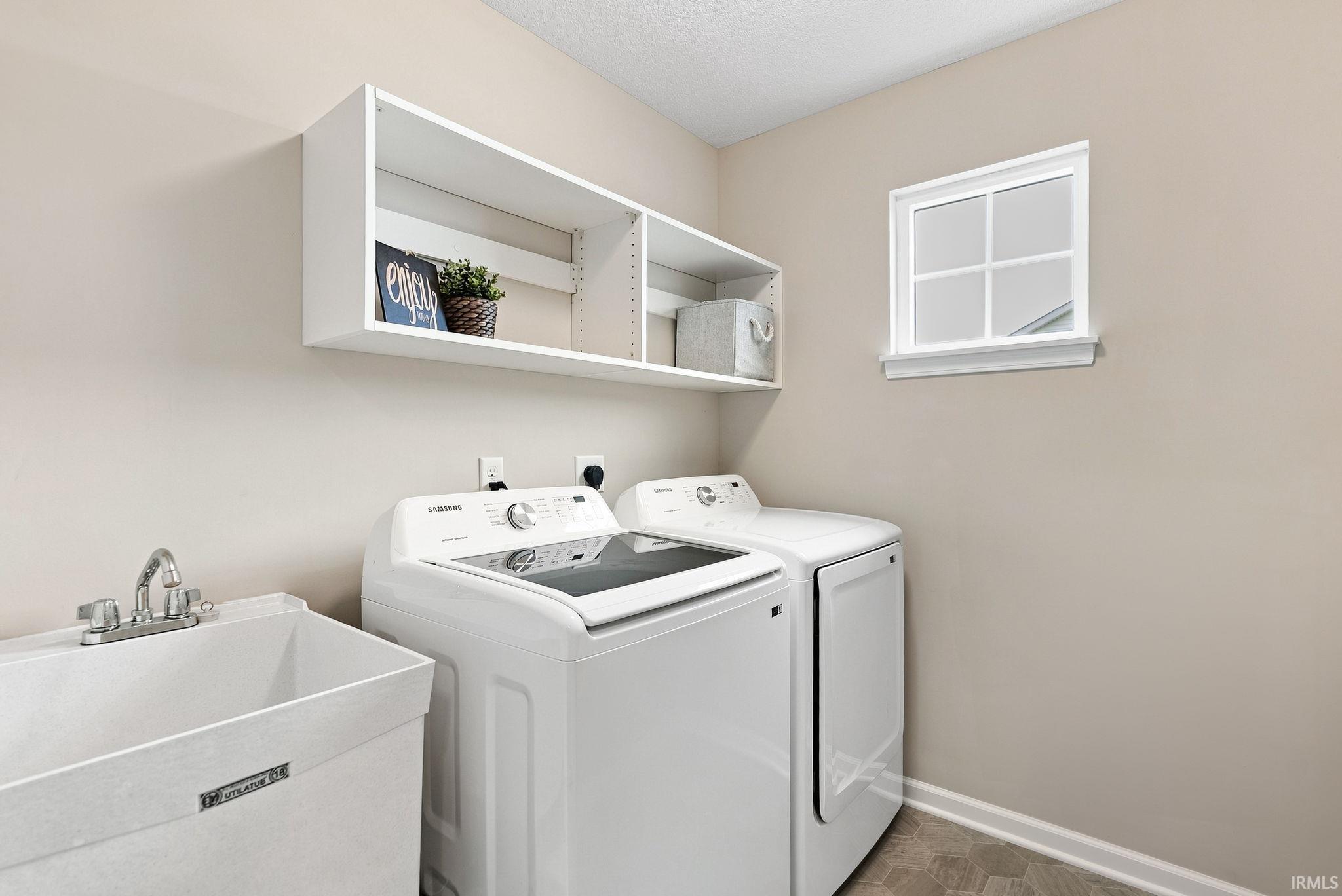 Utility room with a white laundry sink, chrome faucet, and white wall shelving