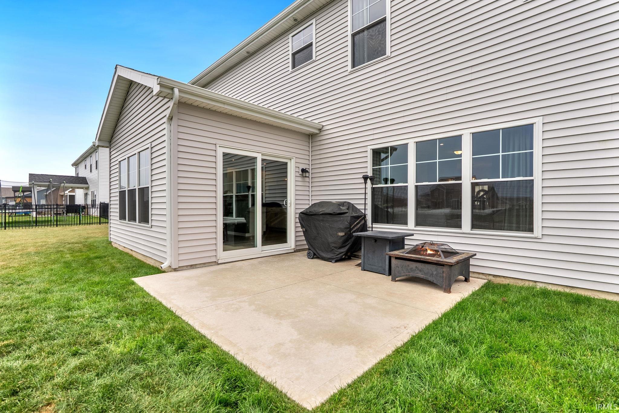 Concrete patio with ample outdoor living space, bordered by a manicured lawn