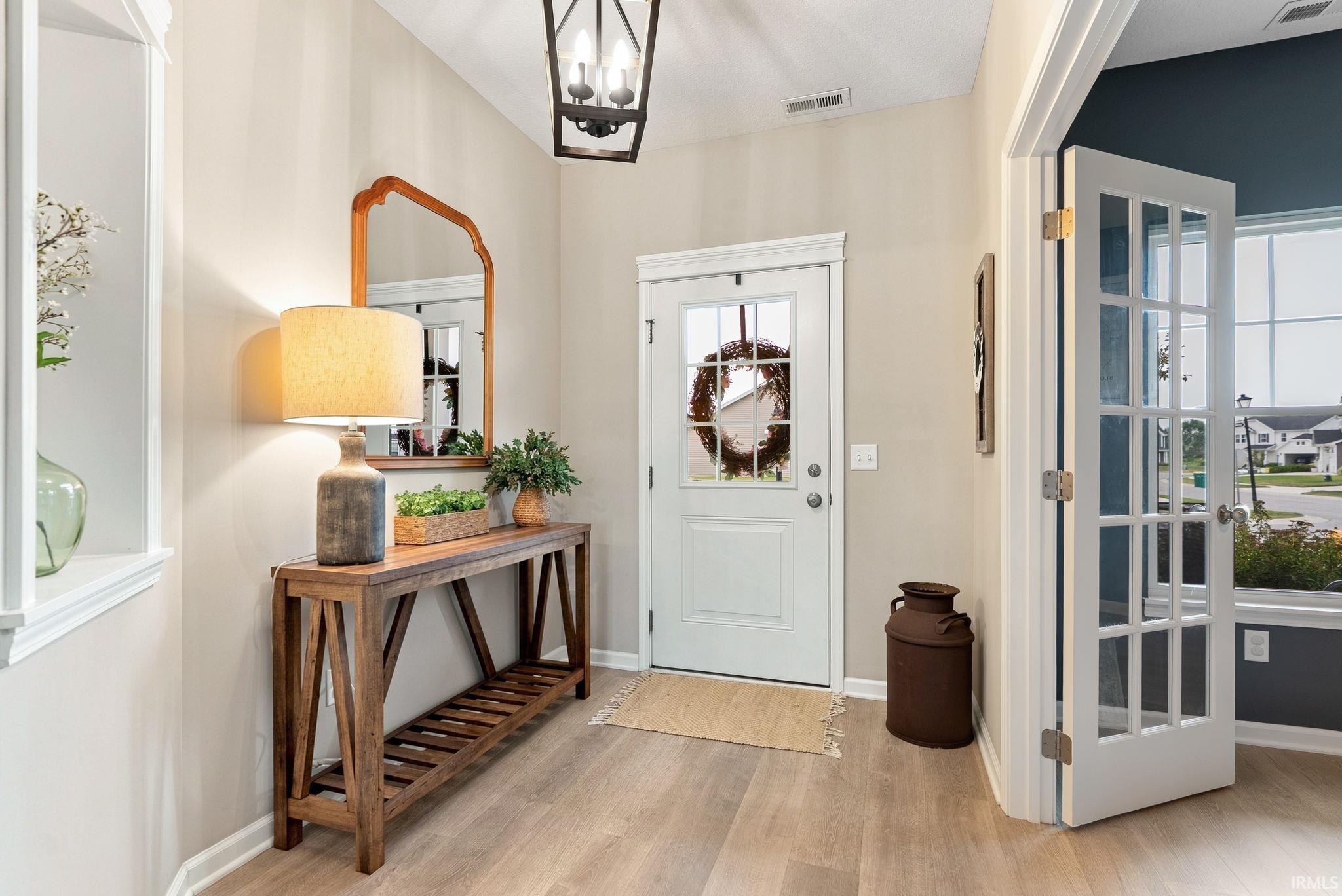 Entryway featuring a white front door with glass panels, light wood-finish flooring, and a contemporary ceiling light fixture