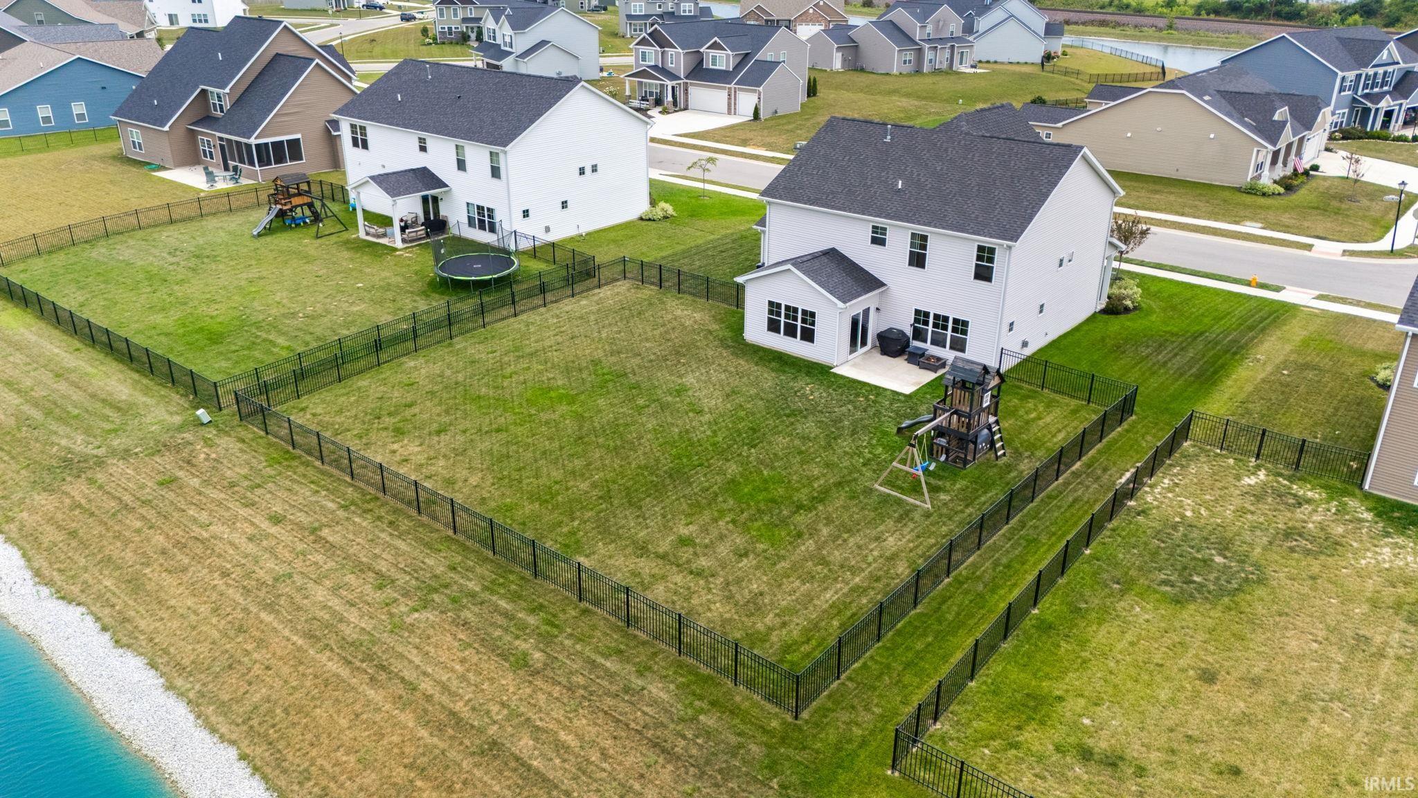 Expansive fenced backyard featuring a substantial lawn and a paved patio area