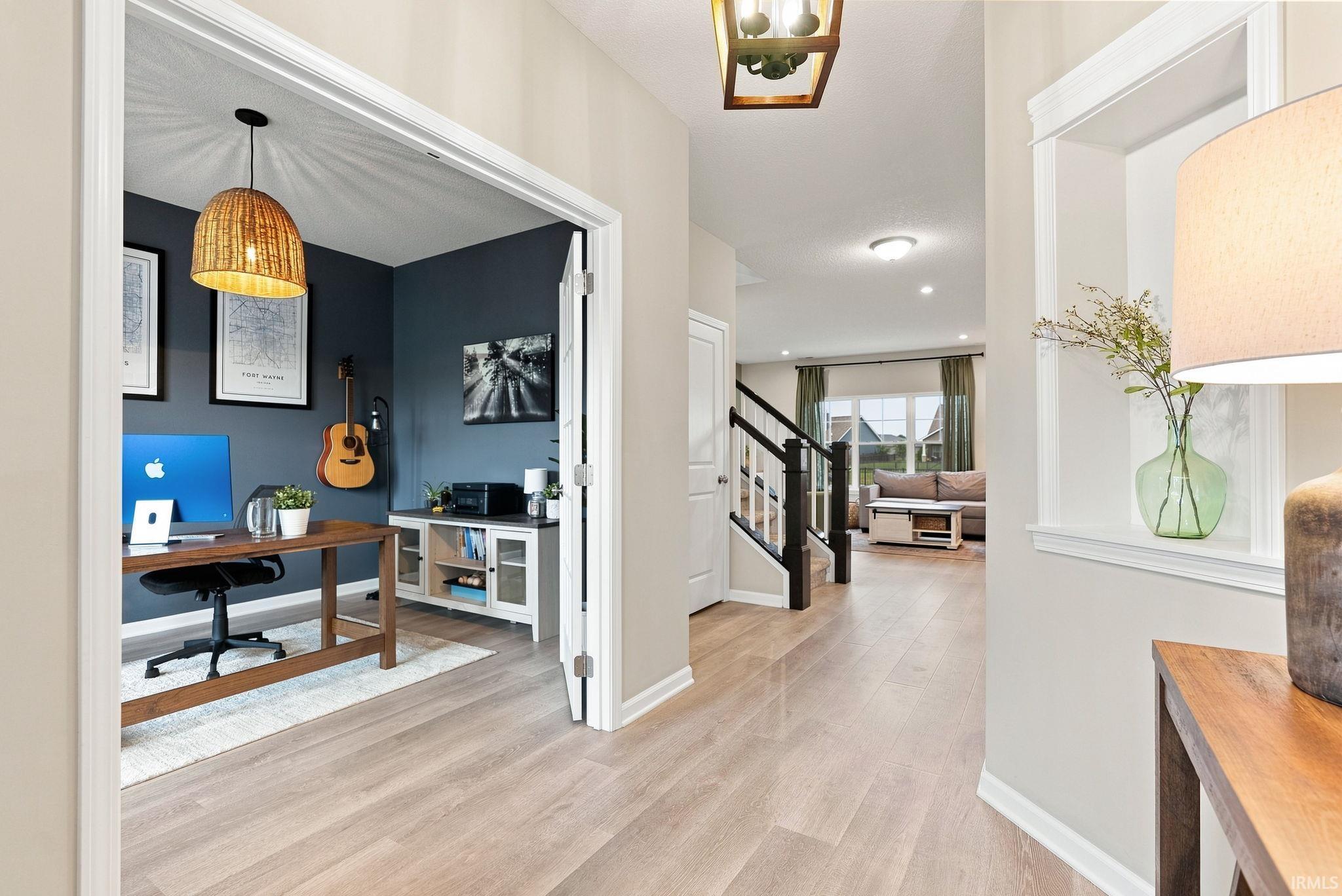 Entryway with wood-finish flooring extending into an open-concept living area and a dedicated room