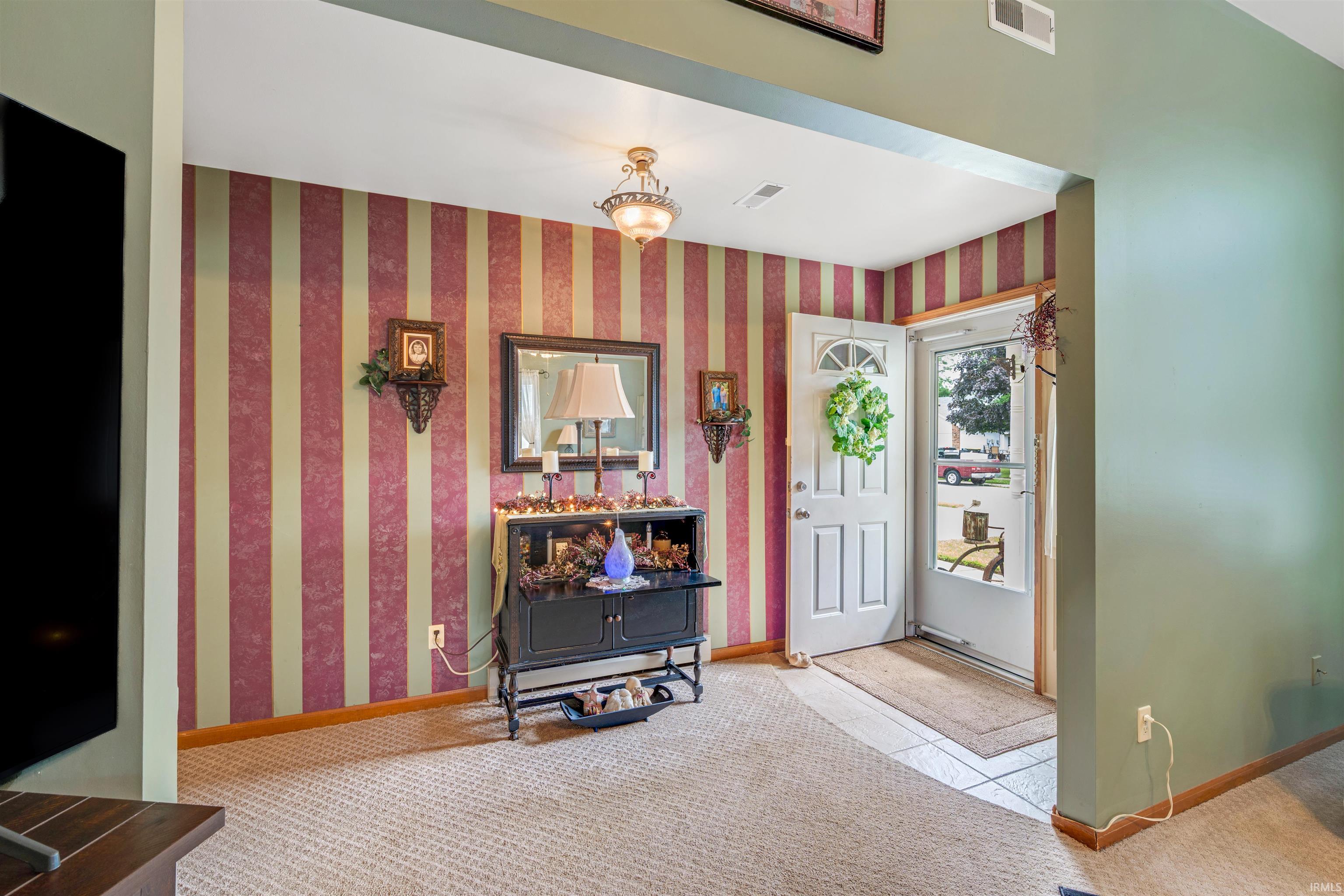 Entryway featuring a white paneled door with an arched glass insert, a storm door with a full-length glass panel, and light-toned tile flooring