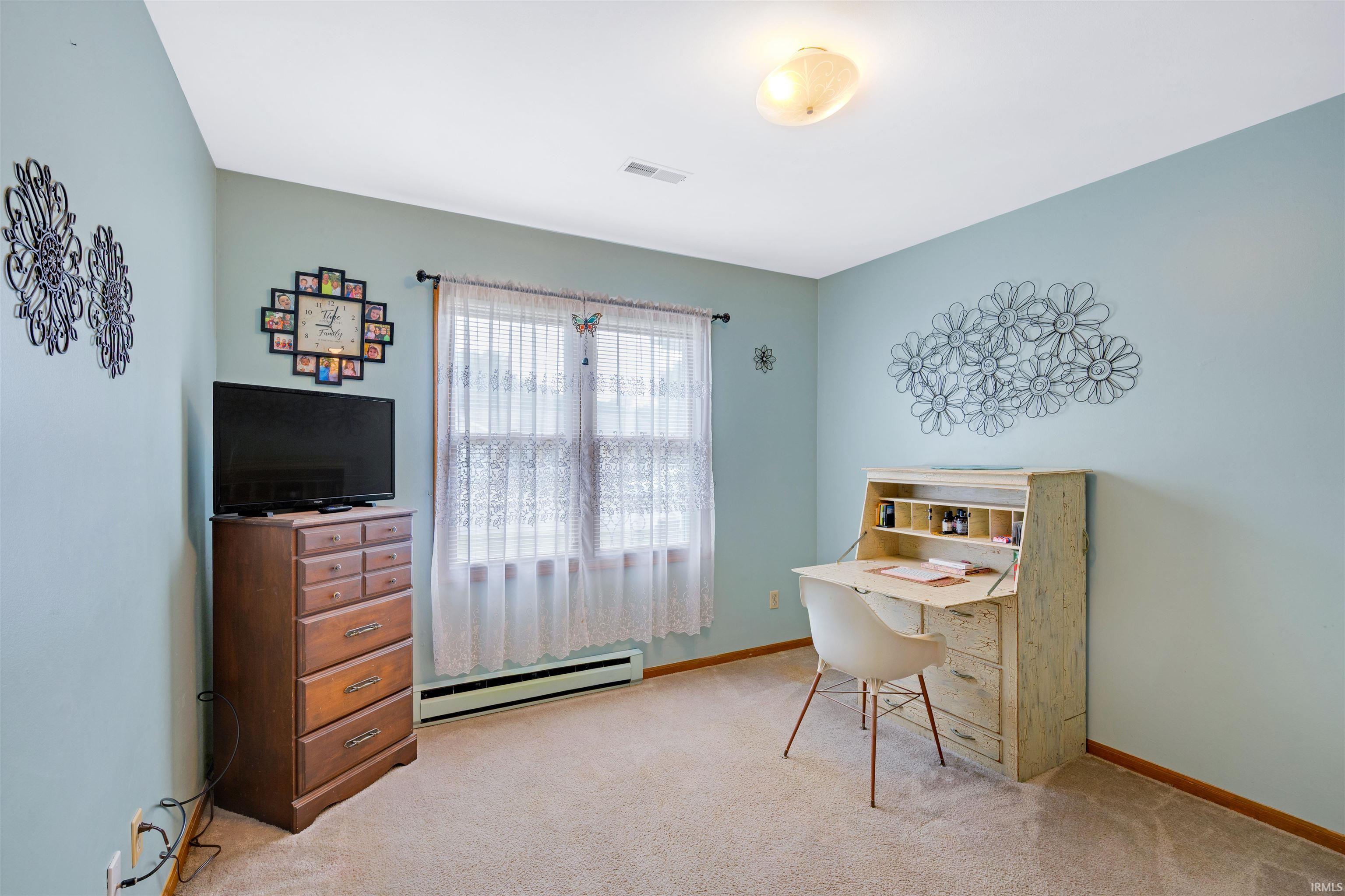 Carpeted room featuring a window with sheer curtains, light blue painted walls, and a ceiling-mounted light fixture