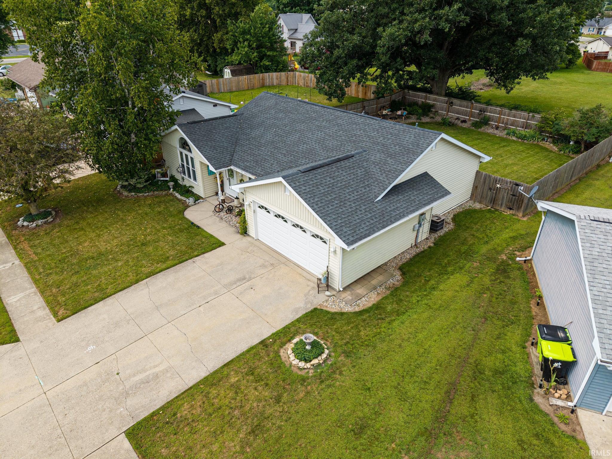 Single-story residence featuring light-toned siding, a dark shingled roof, an attached two-car garage, and a concrete driveway