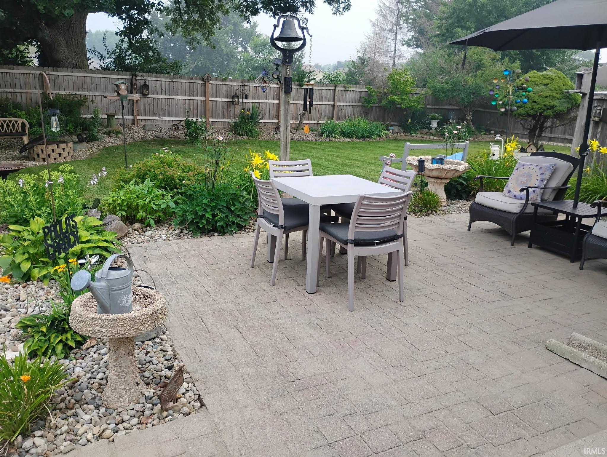 Spacious paver patio with perimeter landscaping and a manicured lawn