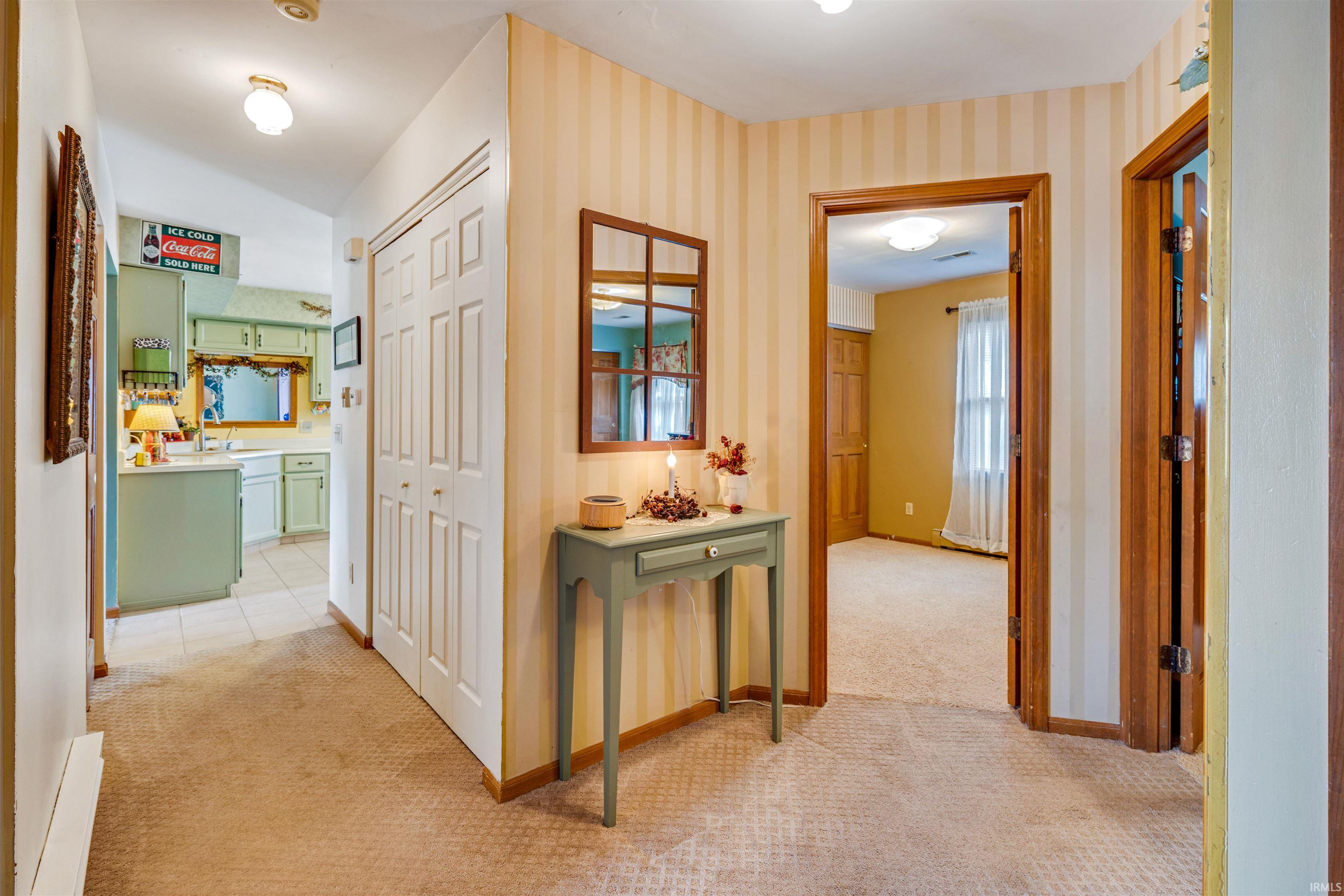 Interior hallway with carpet flooring, a bifold closet door, and a built-in wall mirror