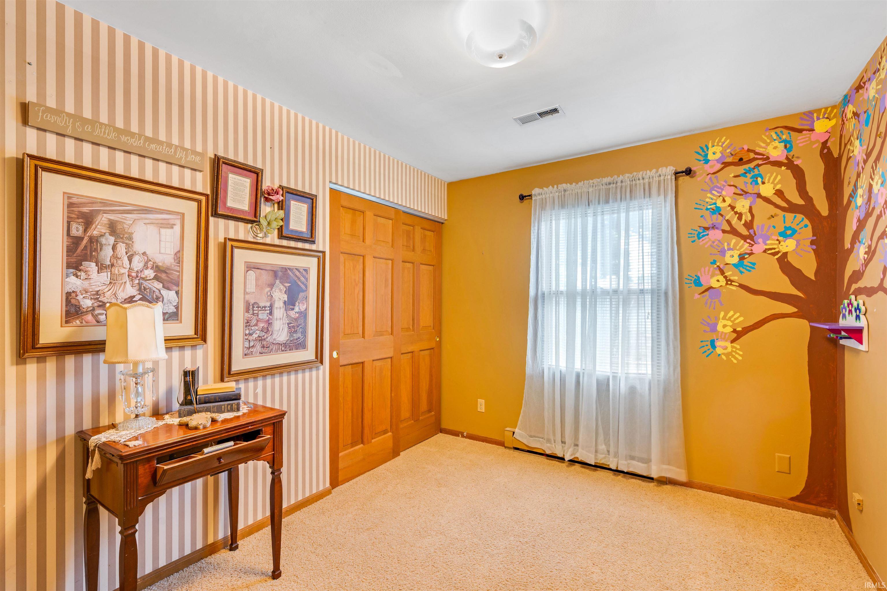 Carpeted room featuring a white ceiling, a single window, and a built-in closet with wood-finish bi-fold doors