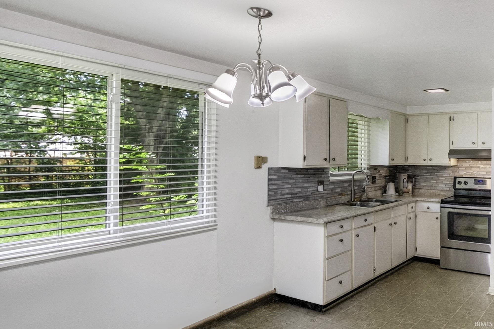 Kitchen featuring white cabinetry, grey granite-style countertops, stainless steel appliances, and a tiled backsplash