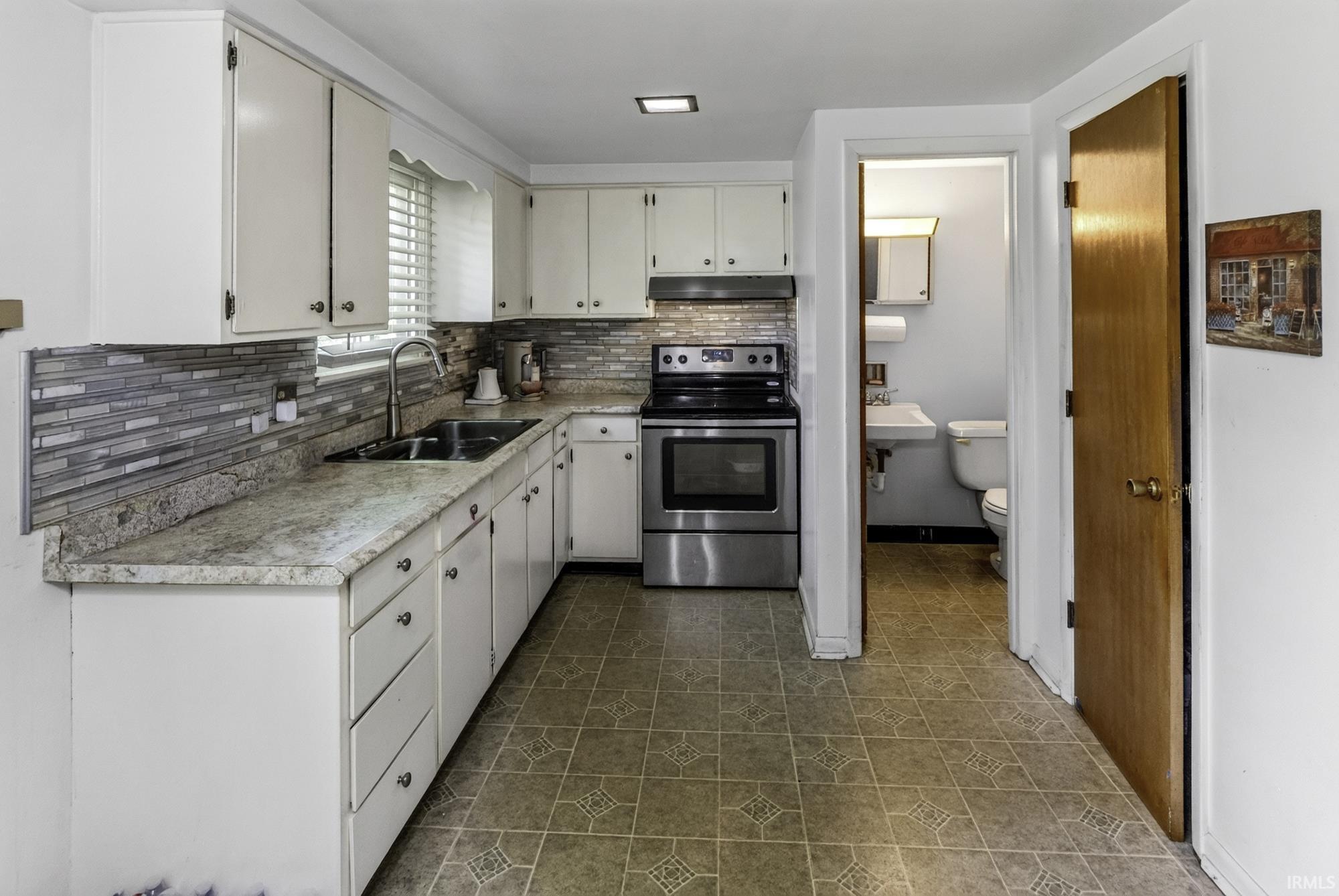 Kitchen featuring white cabinetry, stone-look countertops, and a mosaic tile backsplash