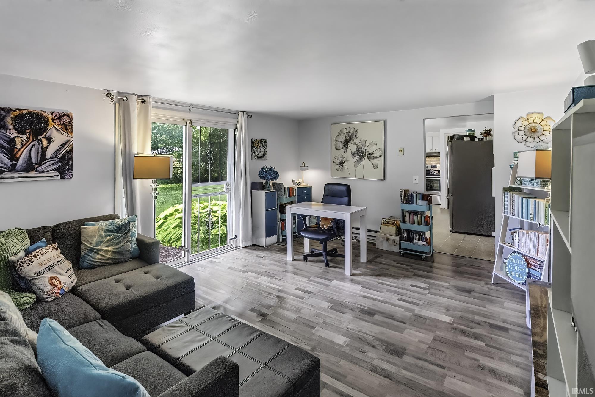Spacious living area featuring wood-finish flooring, light-toned walls, and a sliding glass door providing exterior access