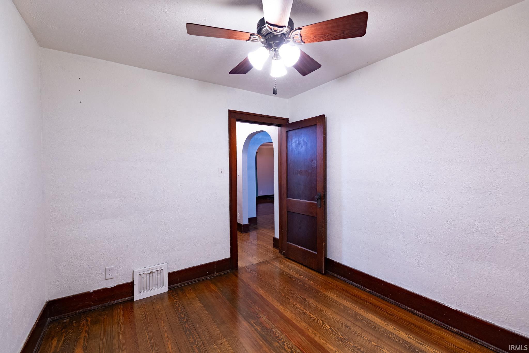 Room featuring wood-finish flooring, white walls, and dark wood trim