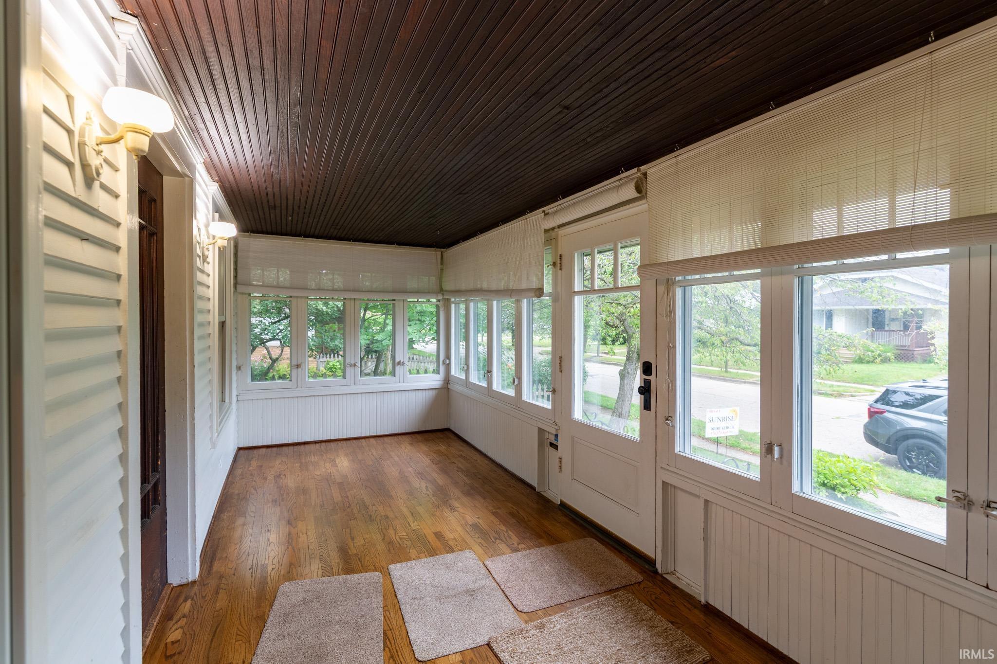 Sunroom with wood-finish flooring and a beadboard ceiling