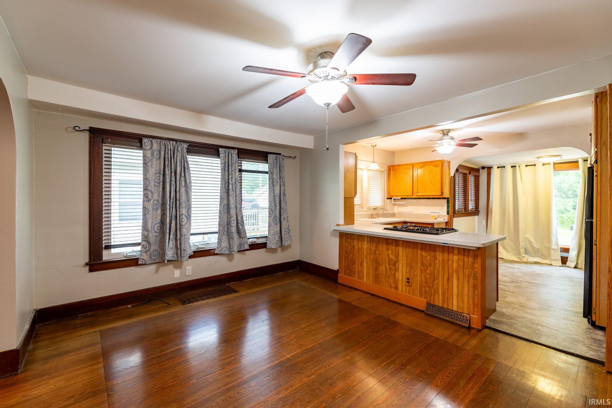 Hardwood flooring throughout, with a ceiling fan and a triple window assembly featuring wood trim