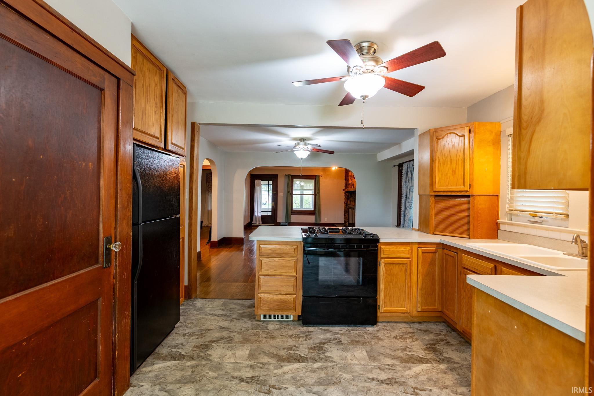 Kitchen featuring wood-finish cabinetry, light-toned countertops, and a black range