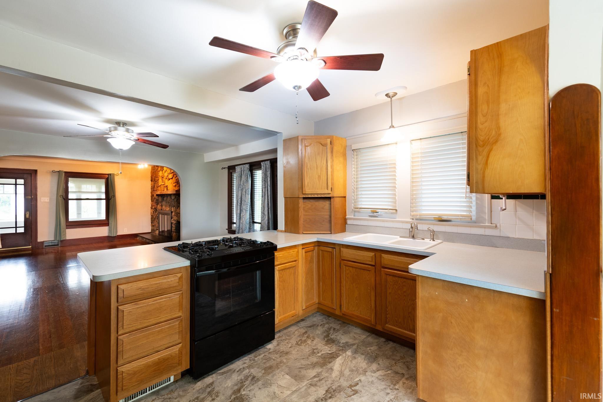 Kitchen featuring wood-finish cabinetry, light-toned countertops, and a double basin sink