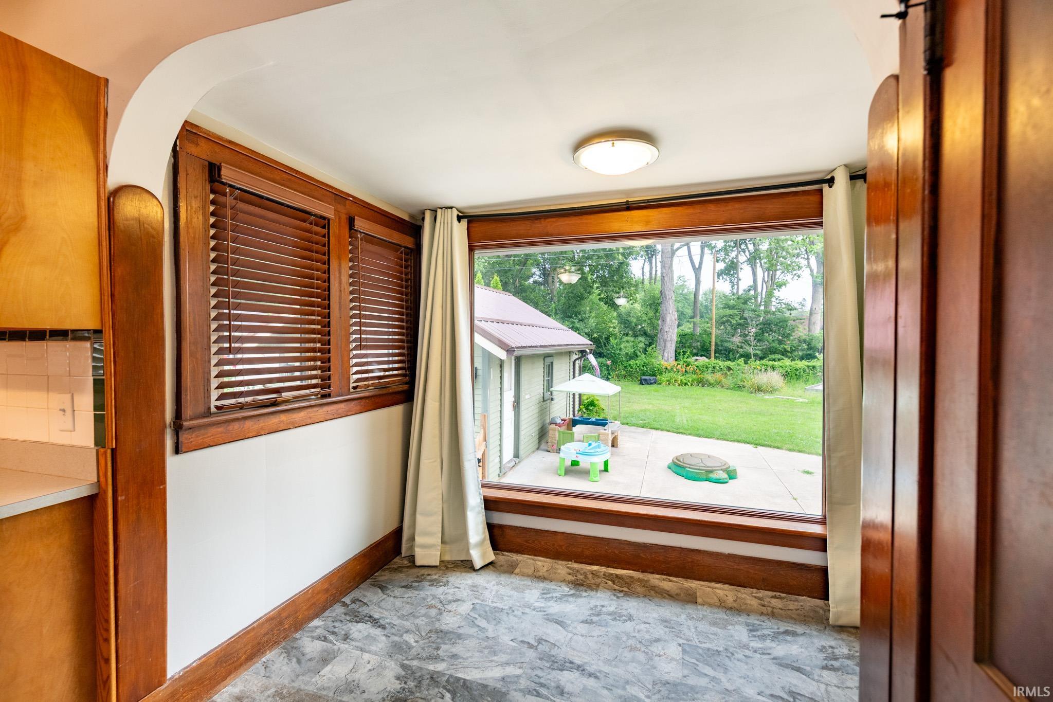 Spacious interior with large picture window overlooking a backyard with a concrete patio