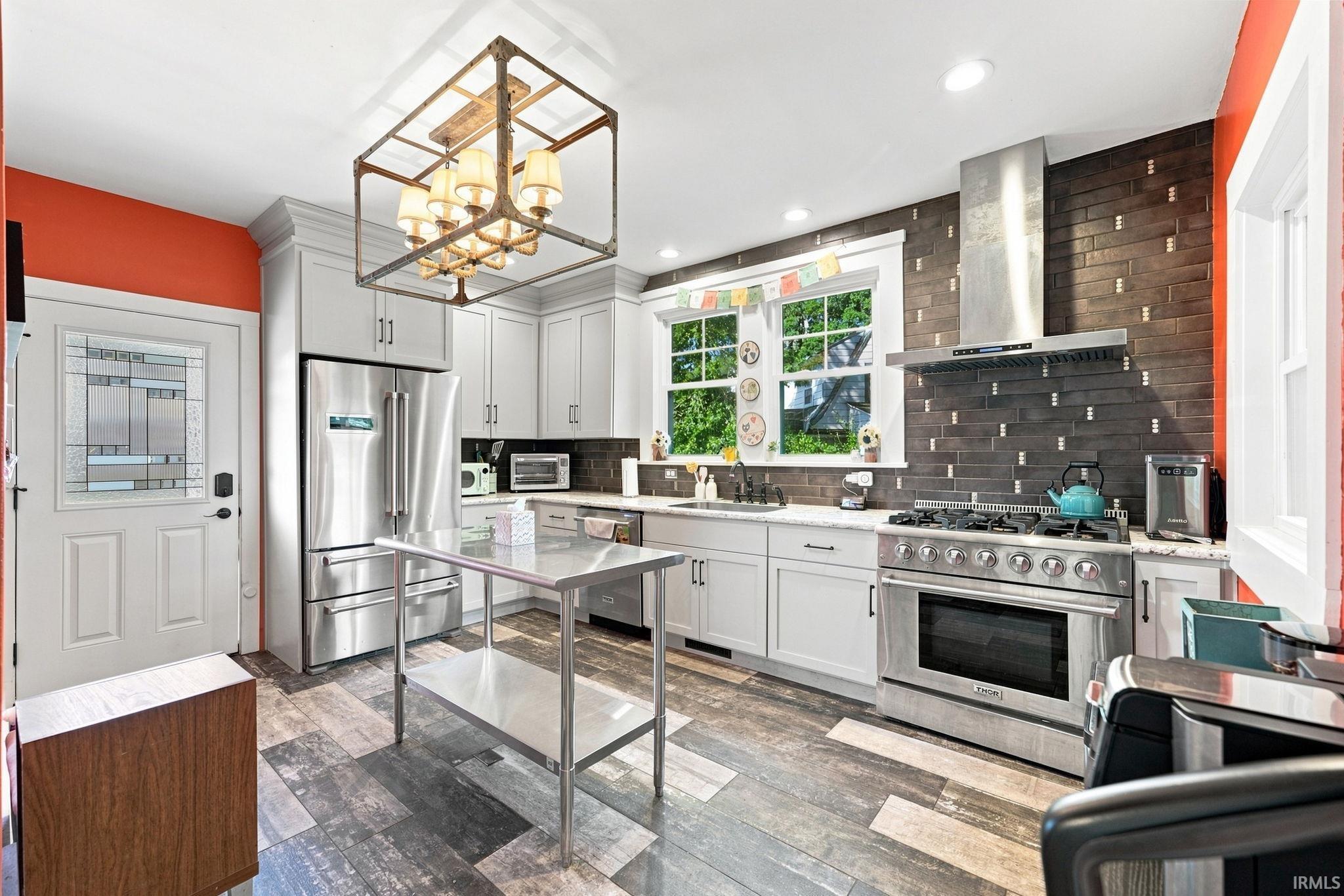Kitchen featuring stainless steel appliances, shaker-style cabinetry, quartz countertops, and wood-finish flooring