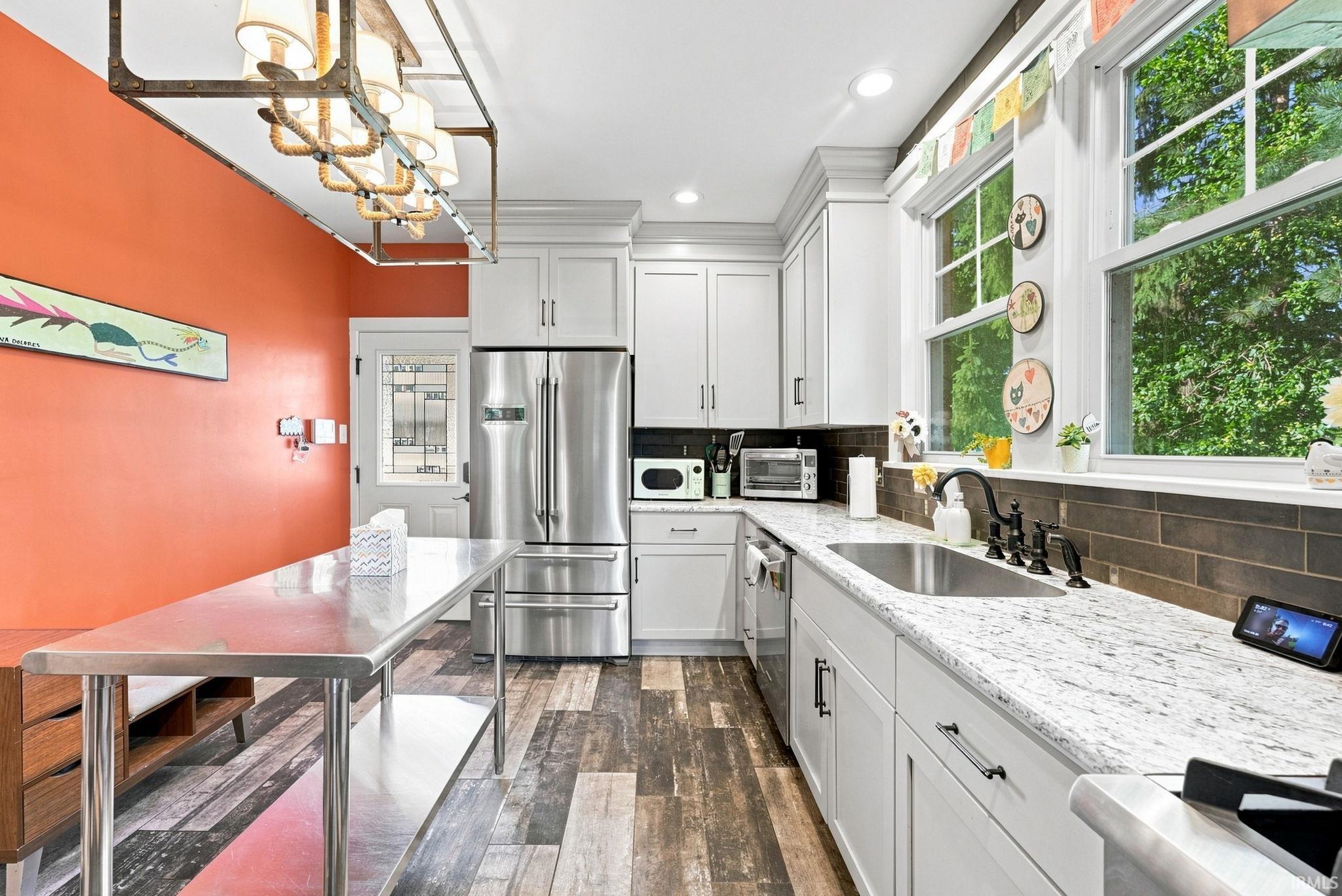 Modern kitchen featuring white shaker cabinetry, stainless steel appliances, speckled stone countertops, and a subway tile backsplash